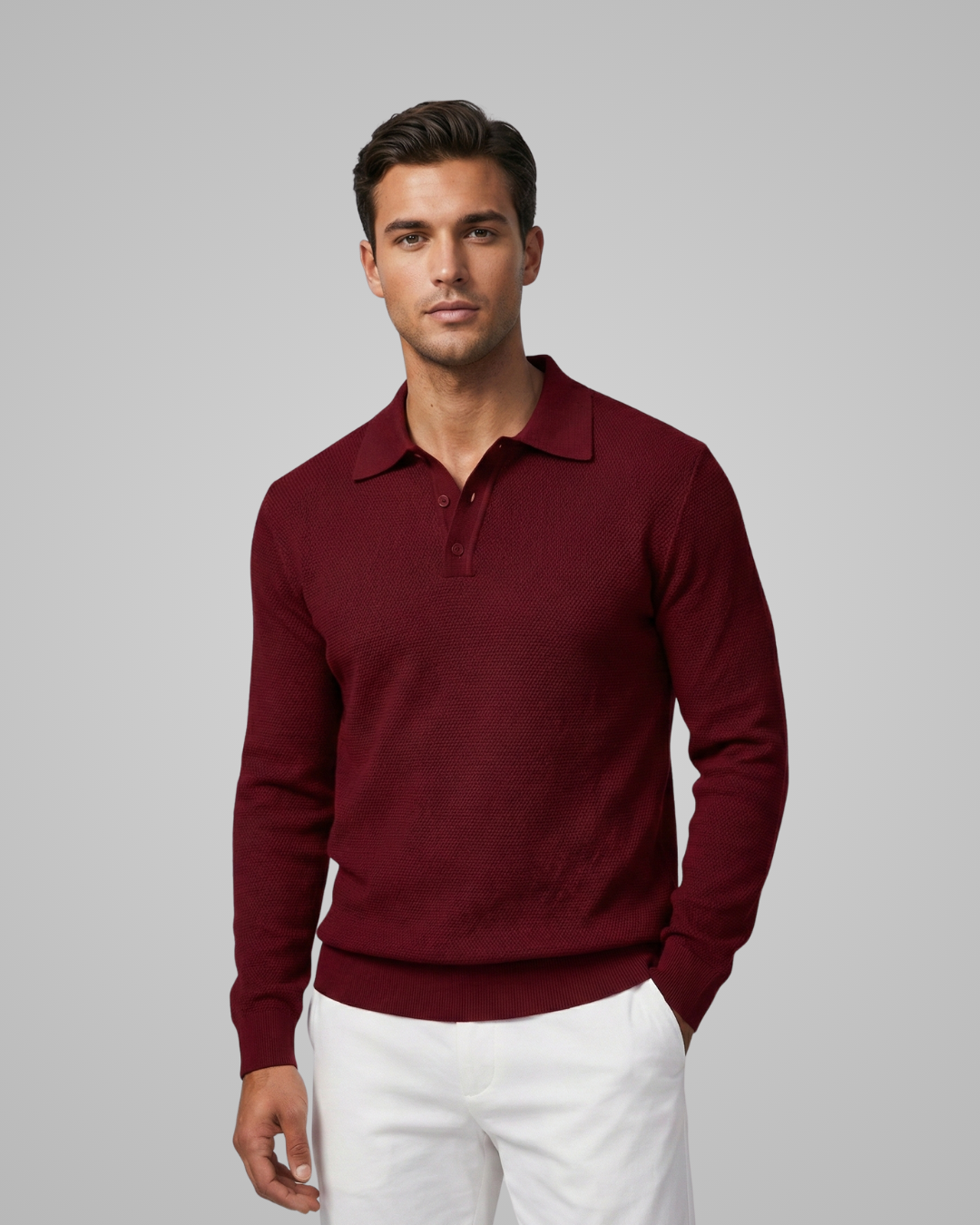 Man wearing a burgundy long-sleeve polo shirt and white pants on a gray background