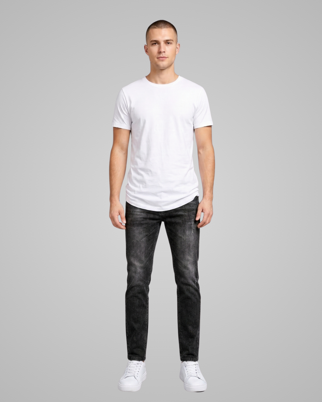 Man wearing a white t-shirt and black jeans on a gray background
