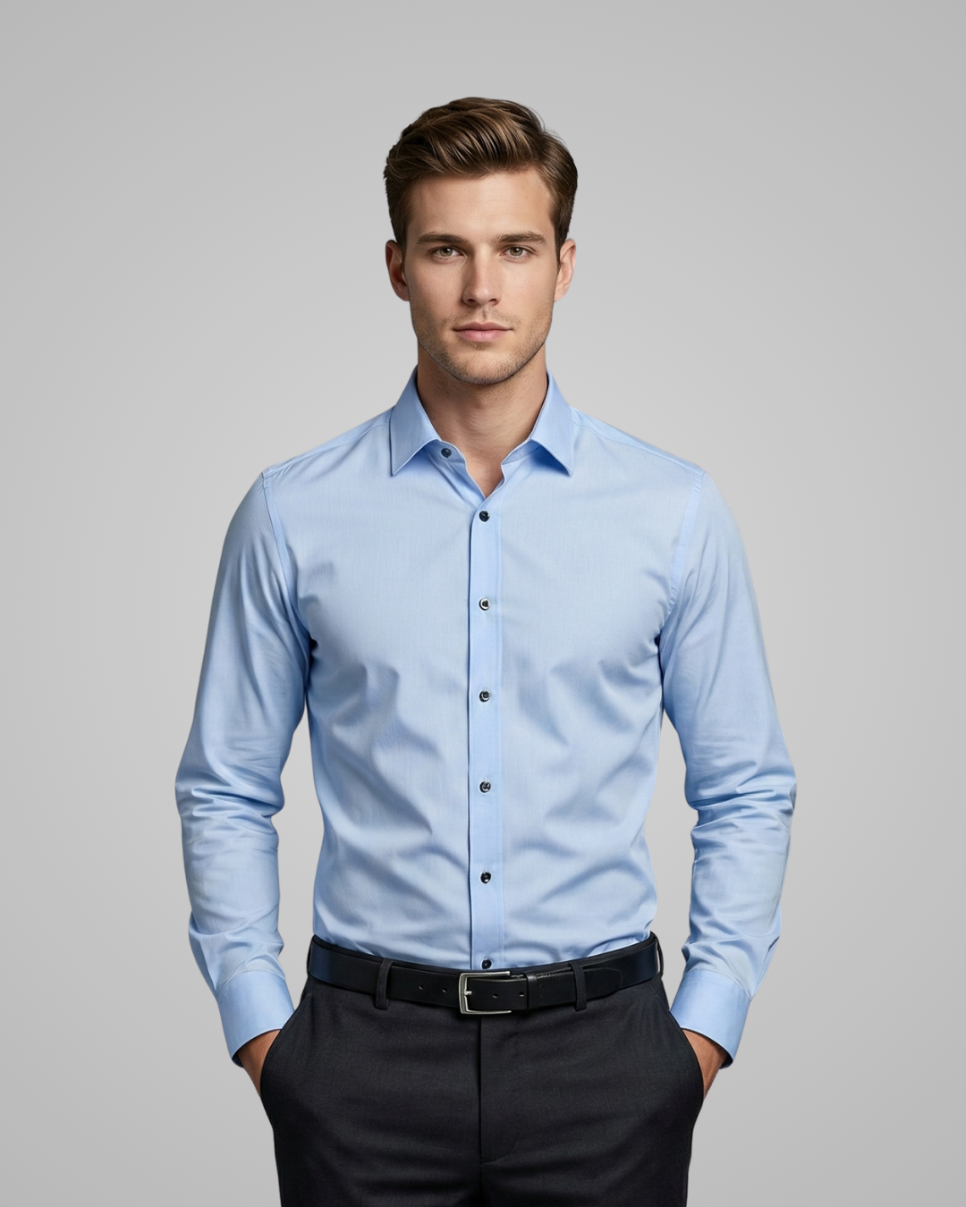 Man wearing a light blue dress shirt and dark pants on a gray background