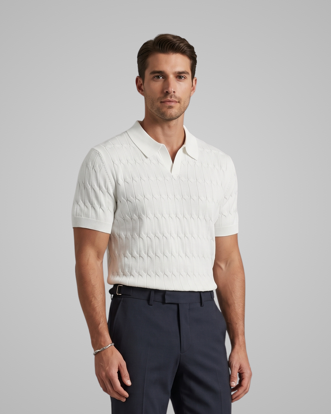 Man wearing a white textured polo shirt and dark pants on a gray background