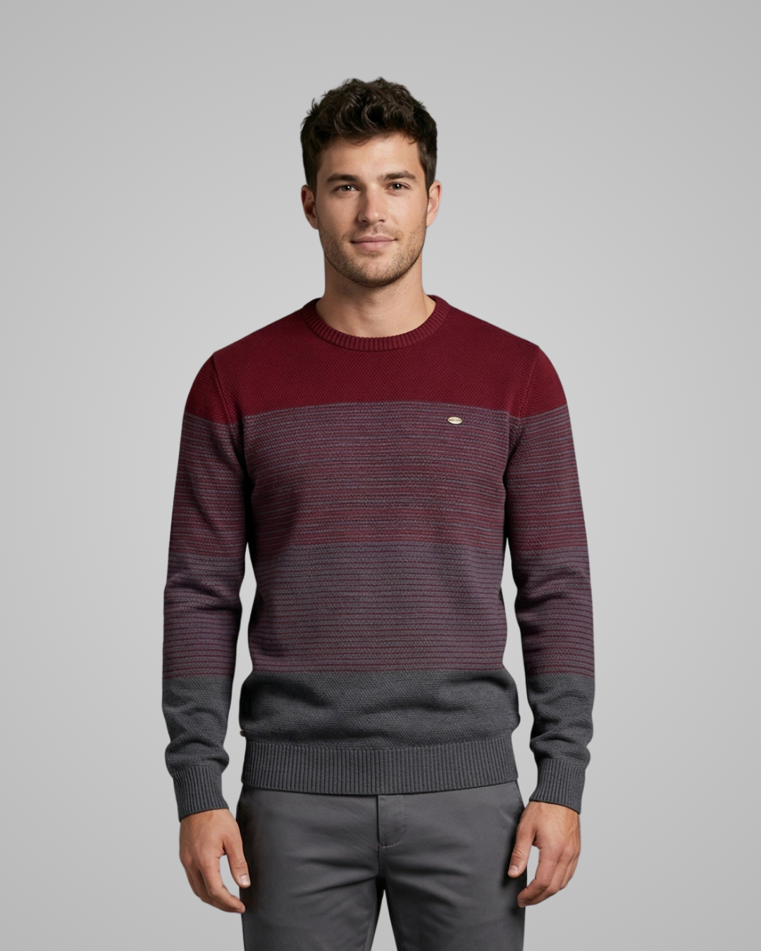 Man wearing a two-tone sweater with a maroon and gray design on a gray background