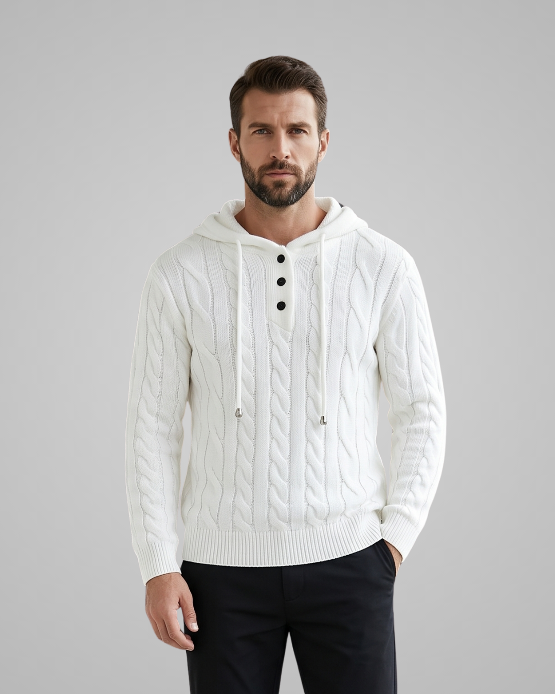 Man wearing a white cable knit hoodie with black buttons on a gray background
