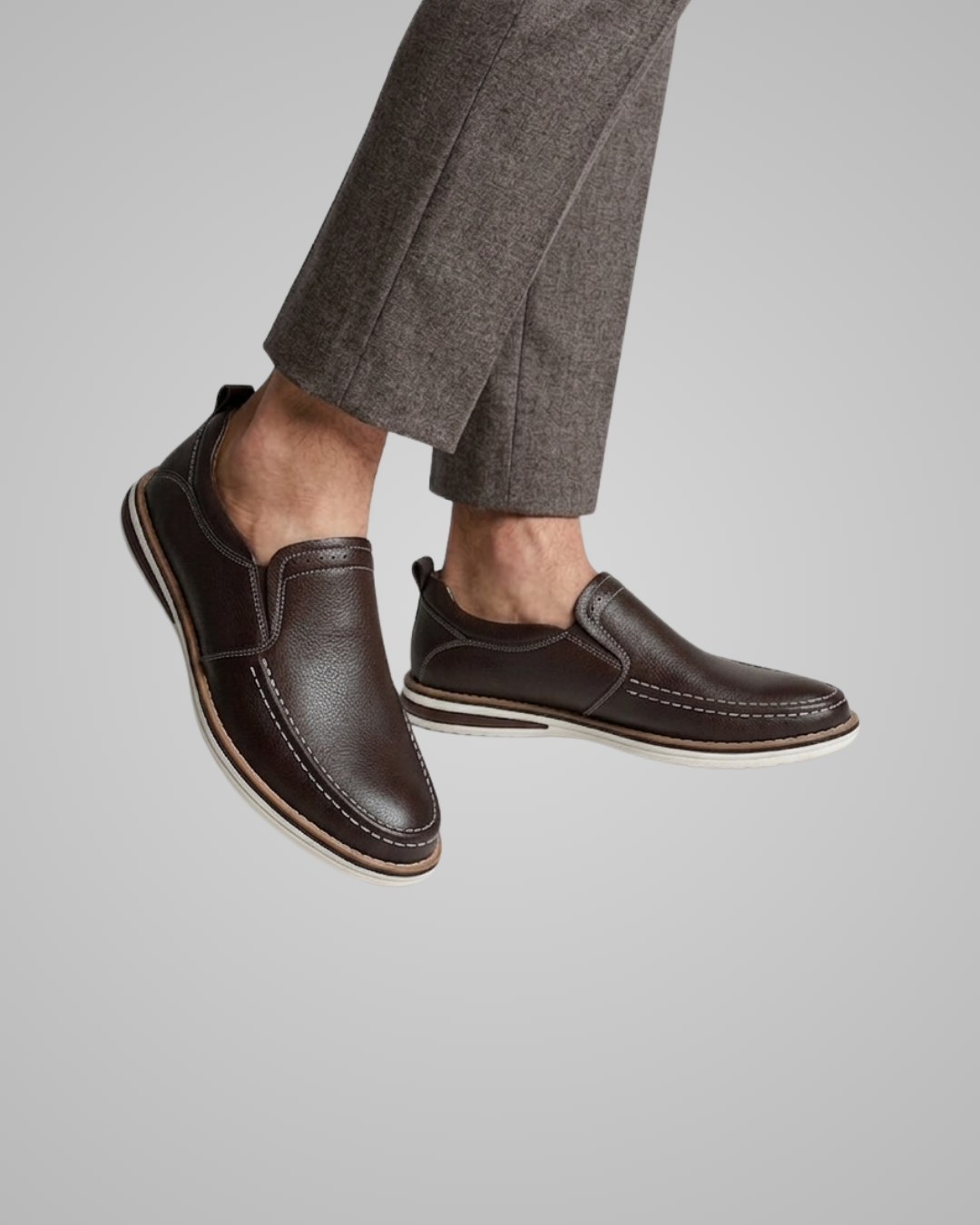 Brown leather shoes worn with gray pants on a light gray background