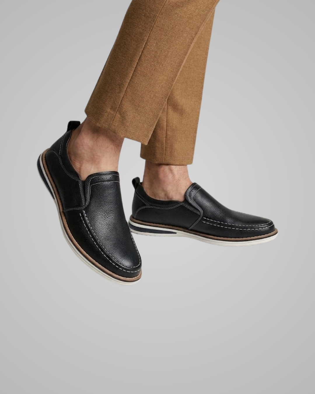Black leather shoes worn with brown pants on a gray background