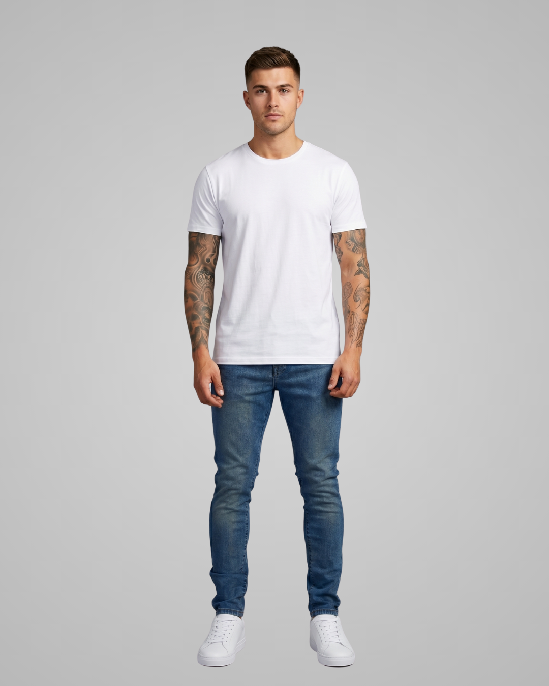 Man wearing a white t-shirt and blue jeans on a gray background