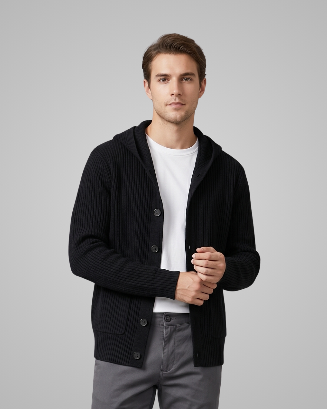 Man wearing a black cardigan over a white shirt with gray pants on a light gray background