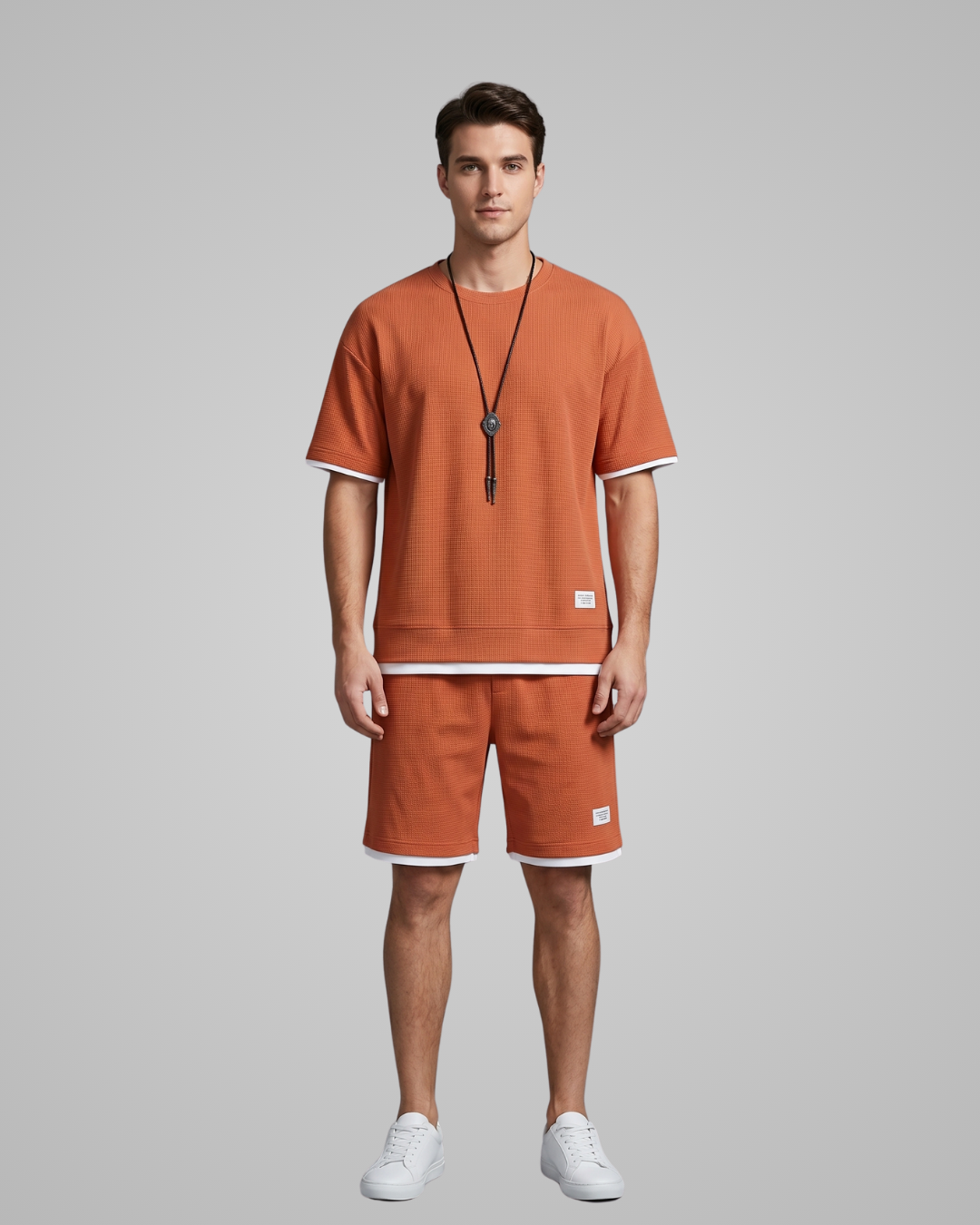 Man wearing a matching orange t-shirt and shorts set on a gray background