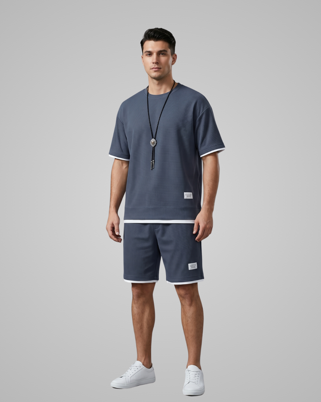 Man wearing a navy blue t-shirt and shorts set on a gray background