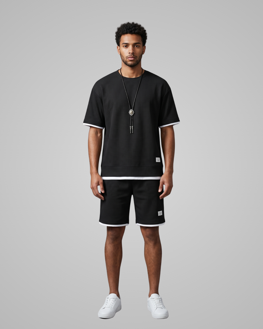 Man wearing a black t-shirt and shorts with white accents on a gray background