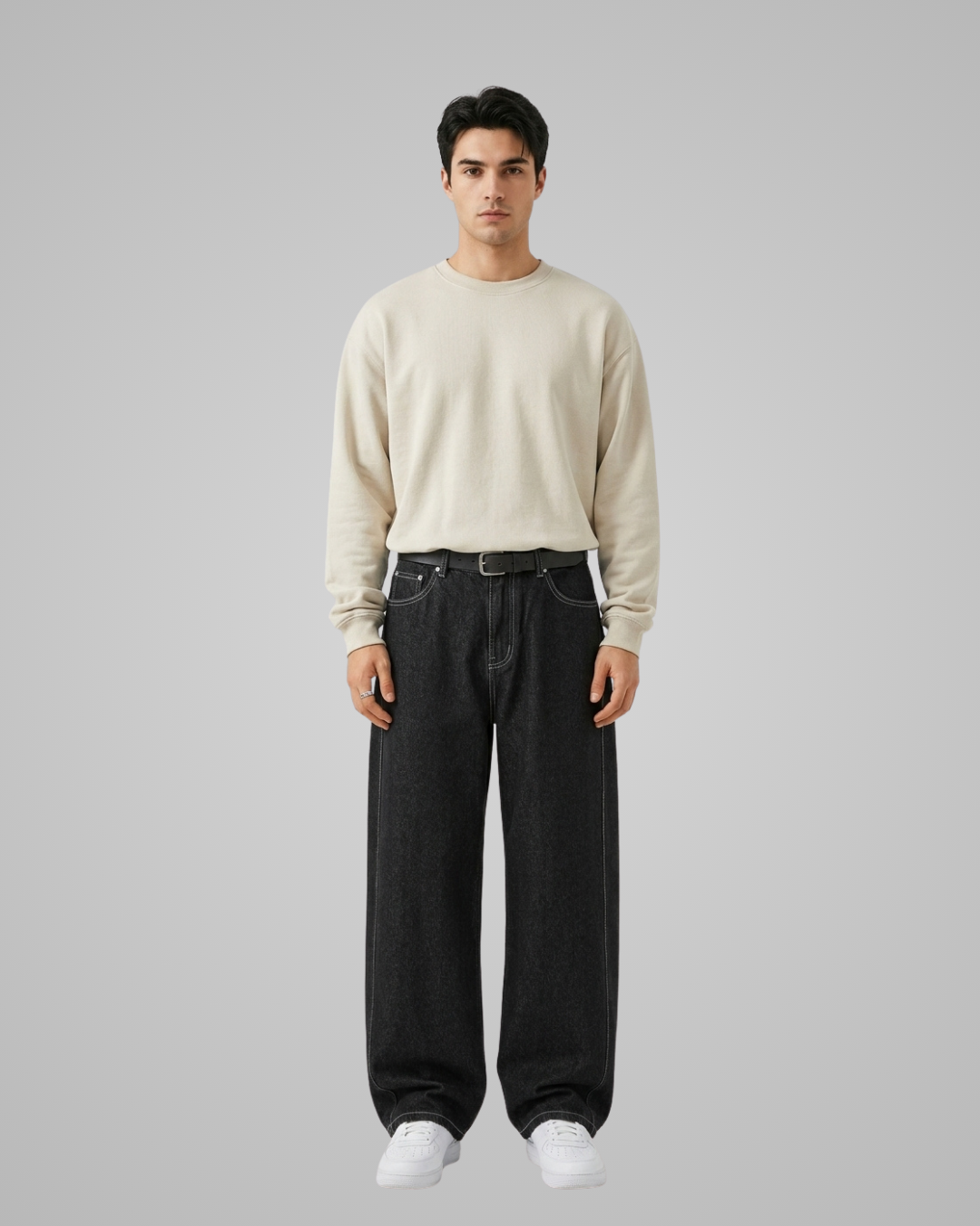 Man wearing a beige sweater and black pants on a gray background
