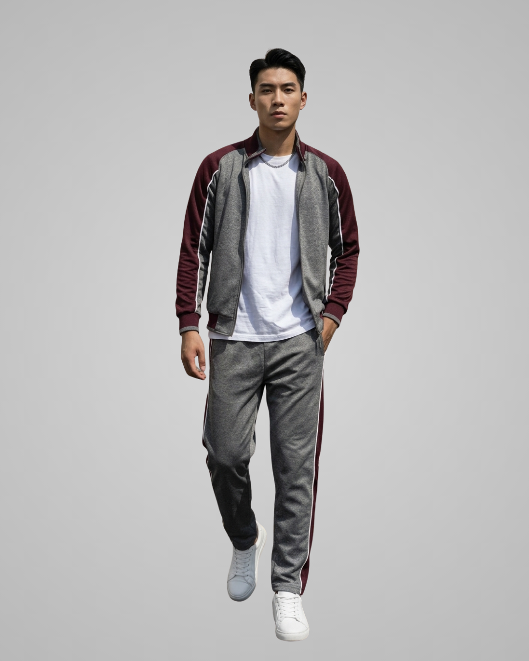 Man wearing a maroon and gray tracksuit with a white shirt on a gray background