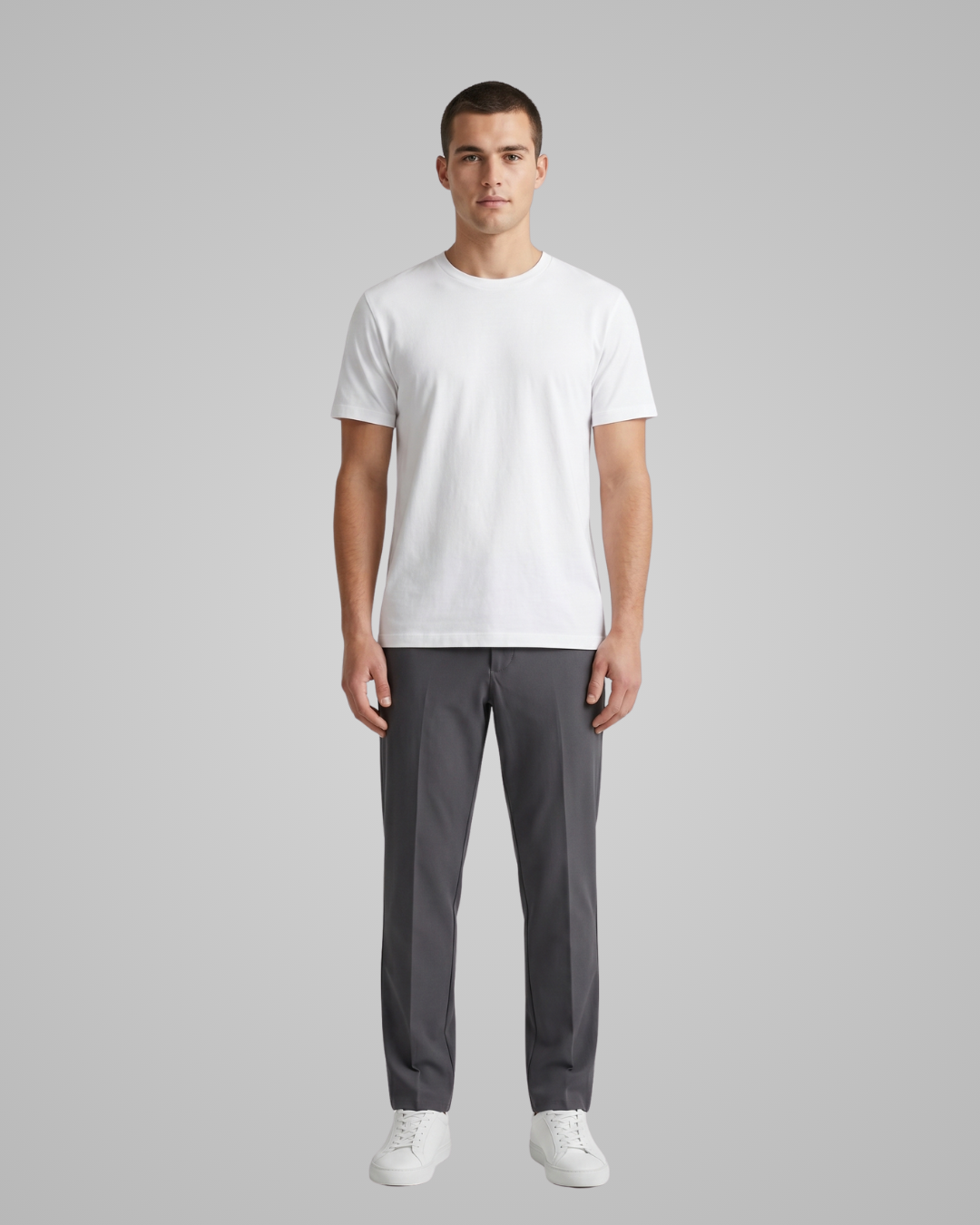Man wearing a white t-shirt and gray pants on a gray background