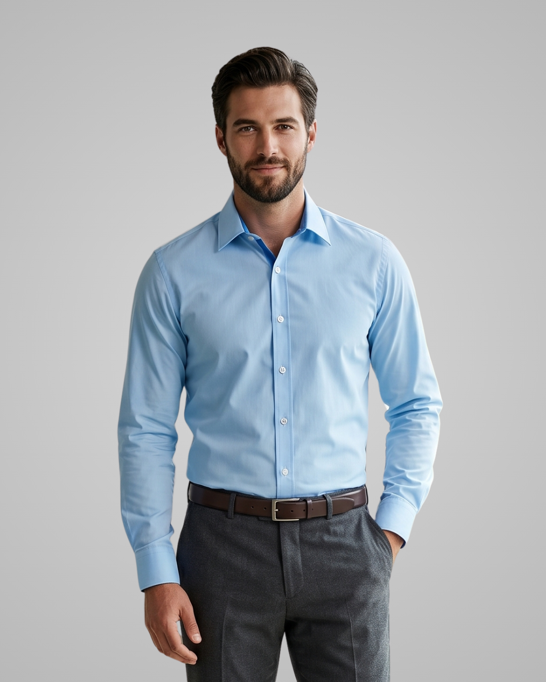 Man wearing a light blue dress shirt and dark pants on a gray background