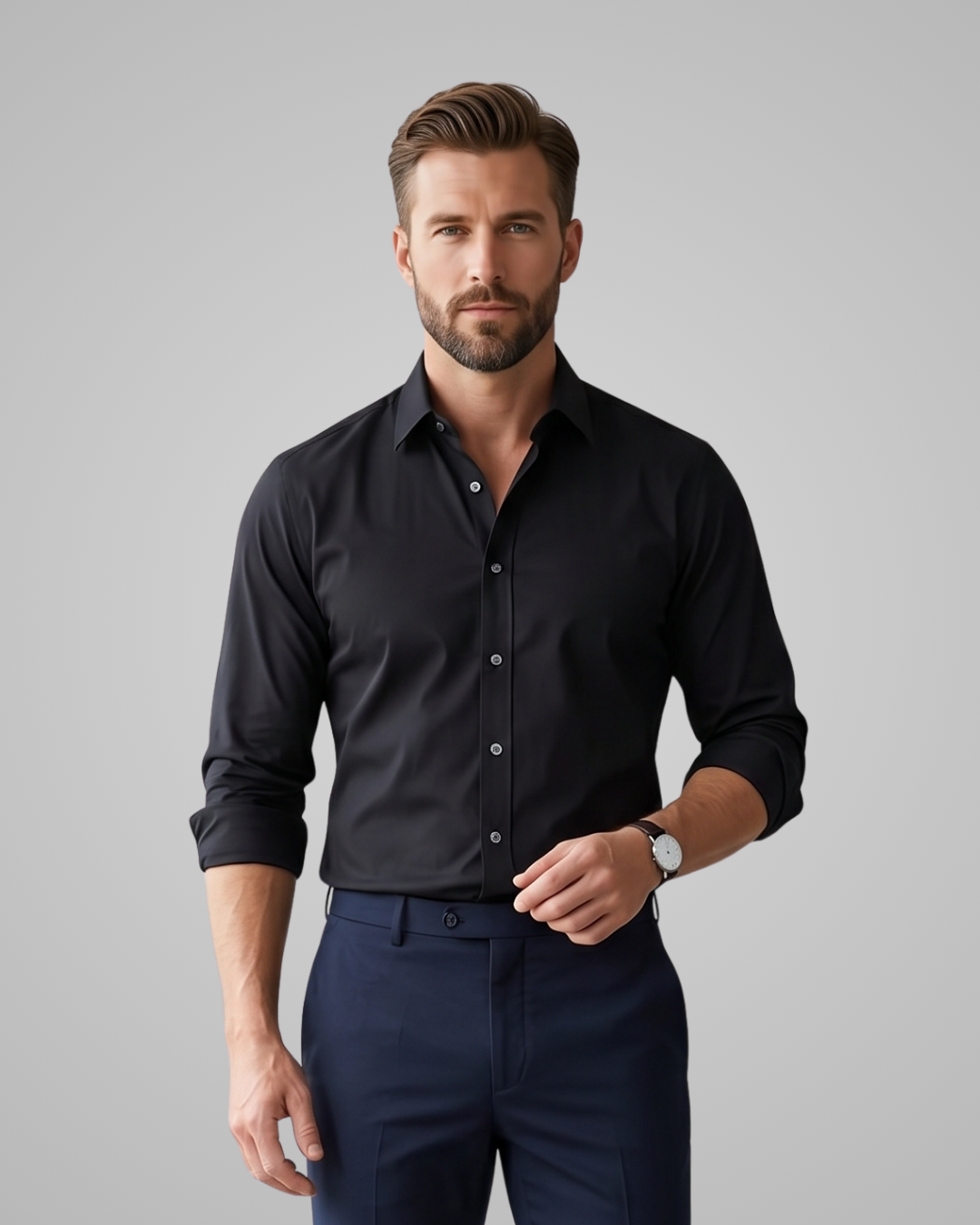 Man wearing a black dress shirt and navy pants against a gray background