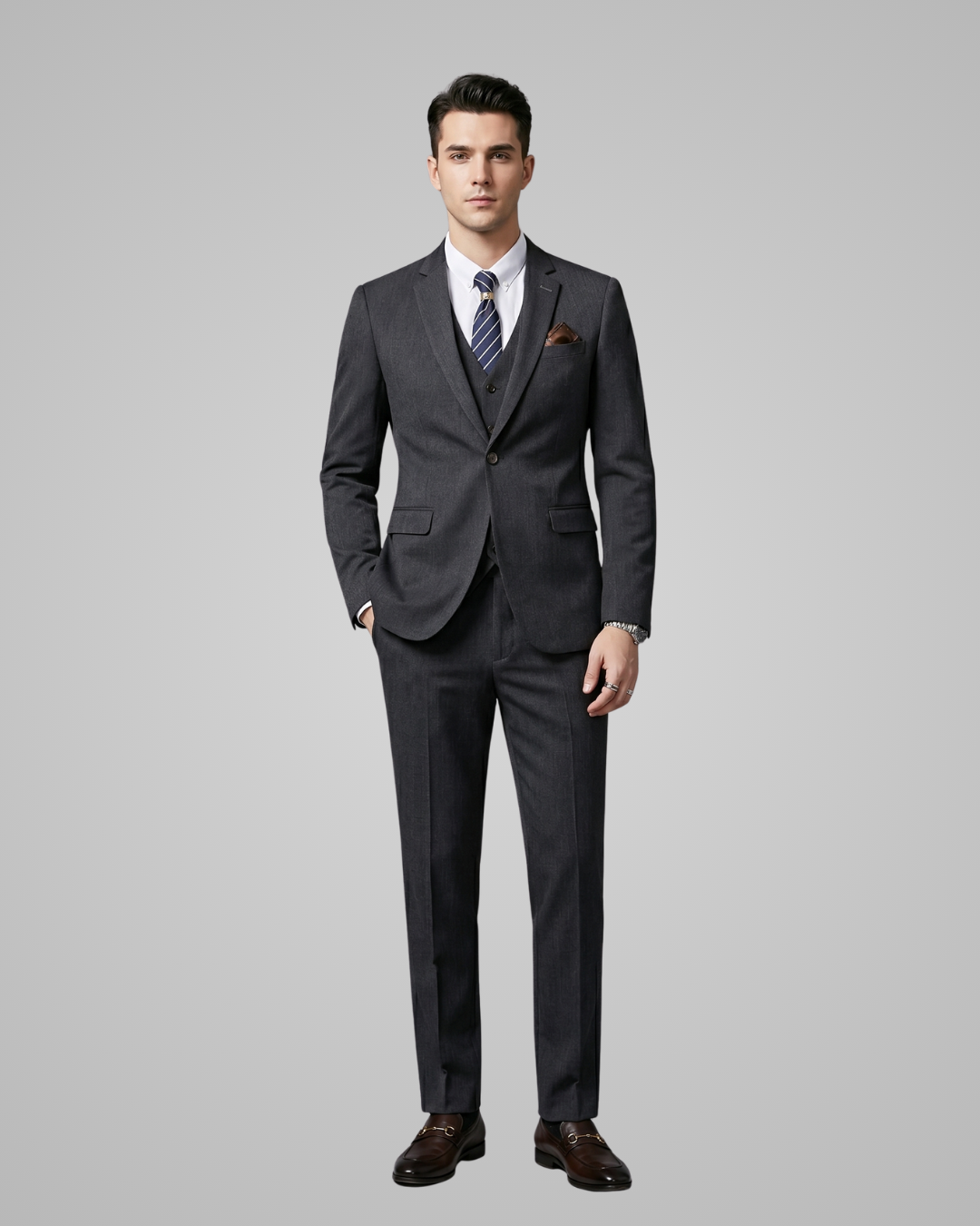Man wearing a dark grey suit with a tie on a gray background