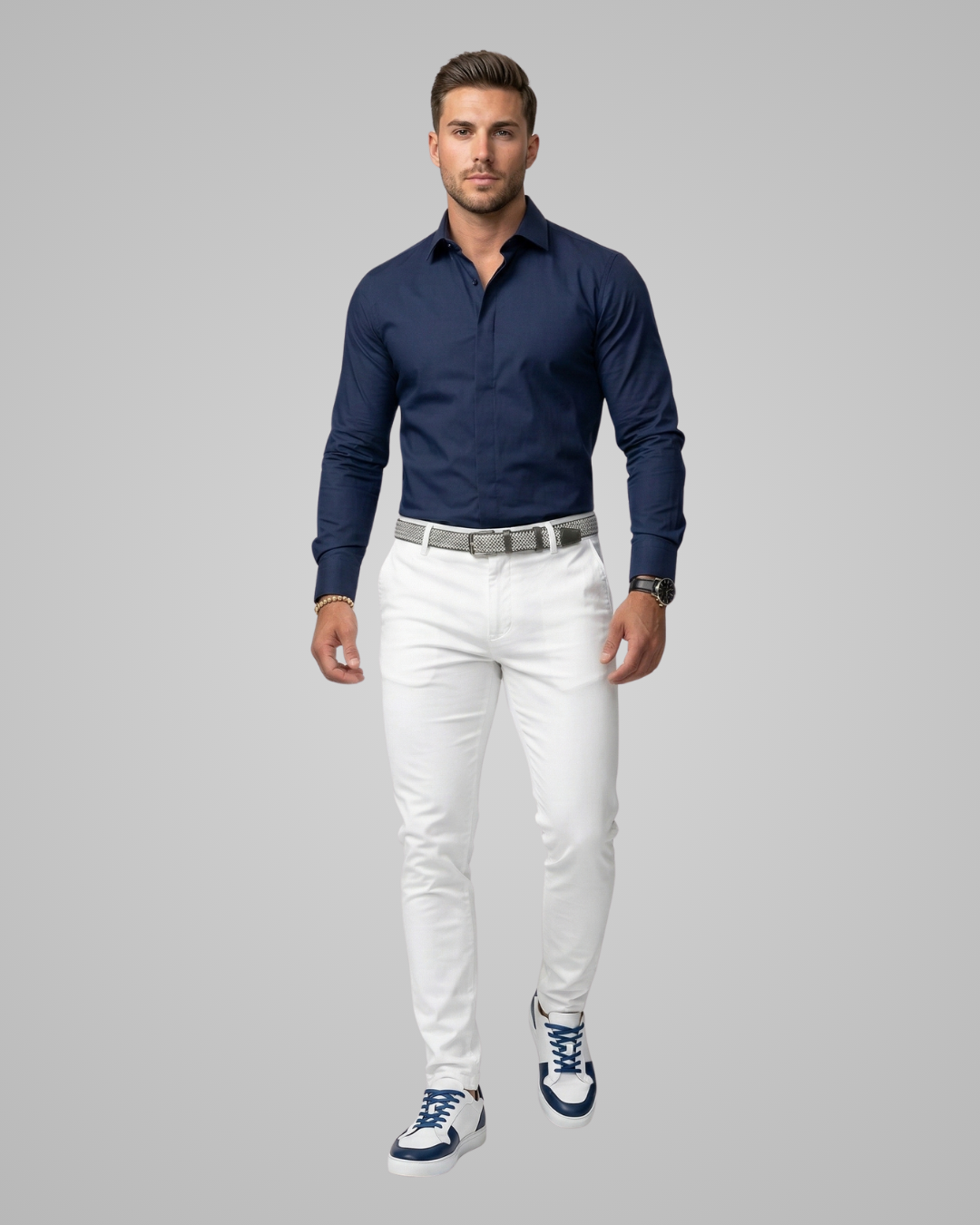 Man wearing a navy shirt, white pants, and blue sneakers on a gray background