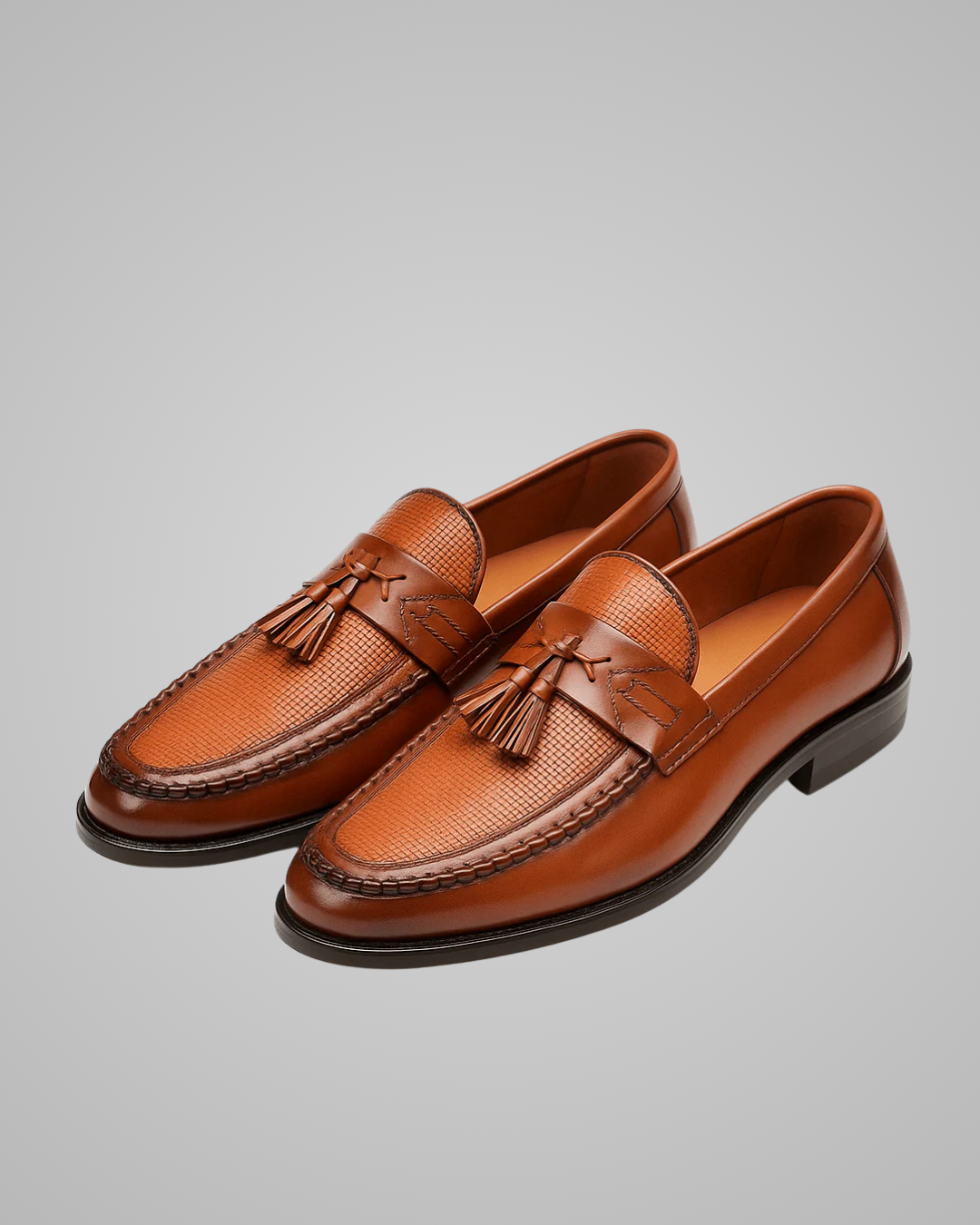 Pair of brown loafers with tassels on a gray background