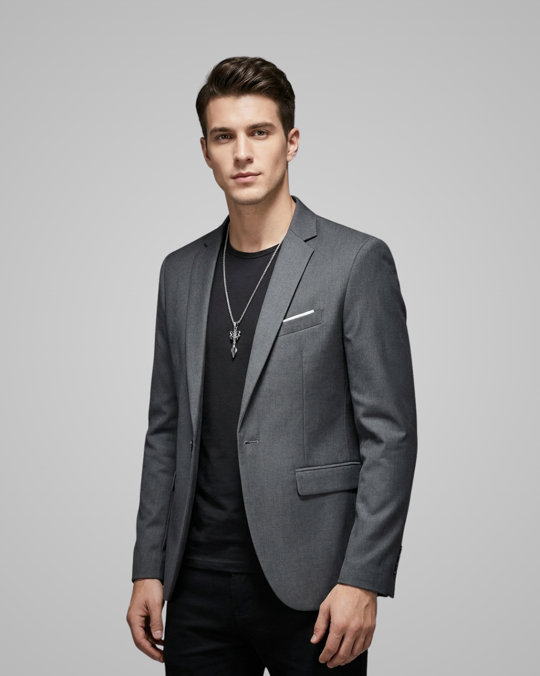 Man wearing a gray blazer over a black shirt on a gray background
