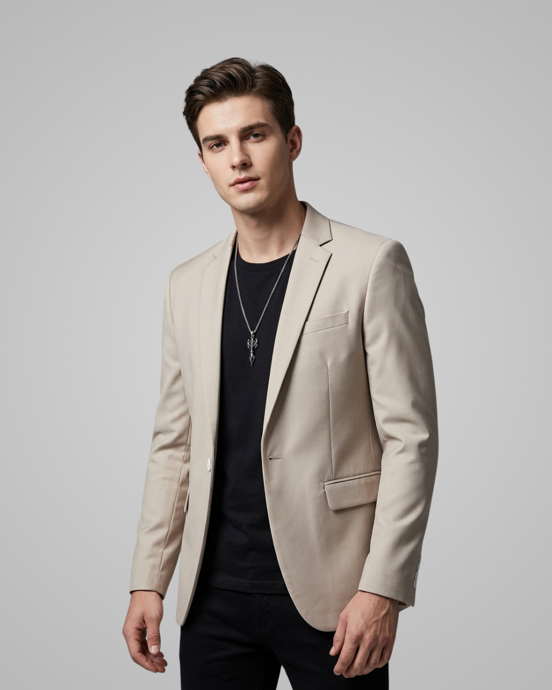 Man wearing a beige blazer over a black shirt on a plain background