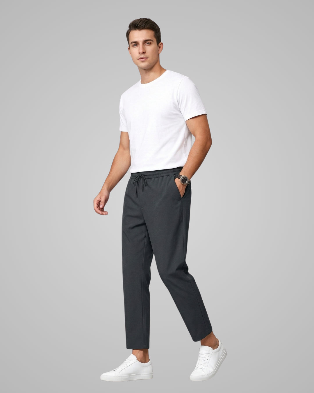 Man wearing a white t-shirt and dark pants on a gray background