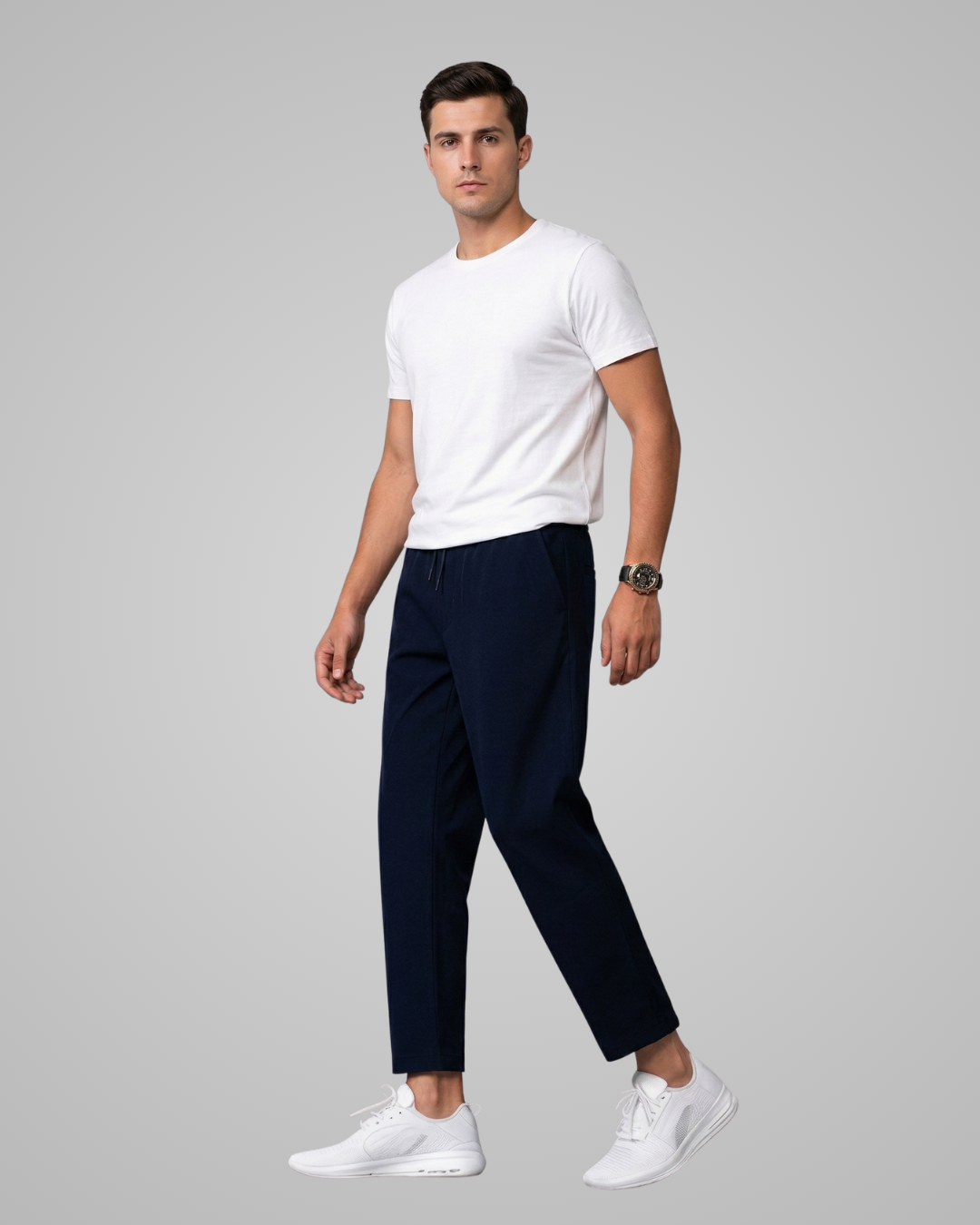 Man wearing a white t-shirt and navy pants on a gray background