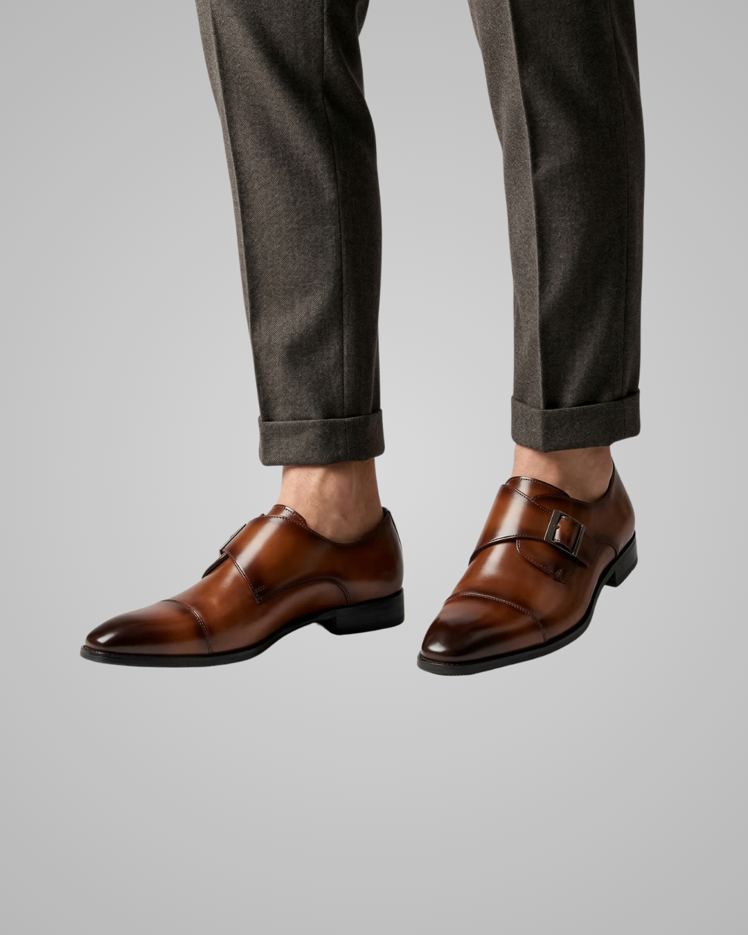 Brown dress shoes worn with gray pants on a light gray background