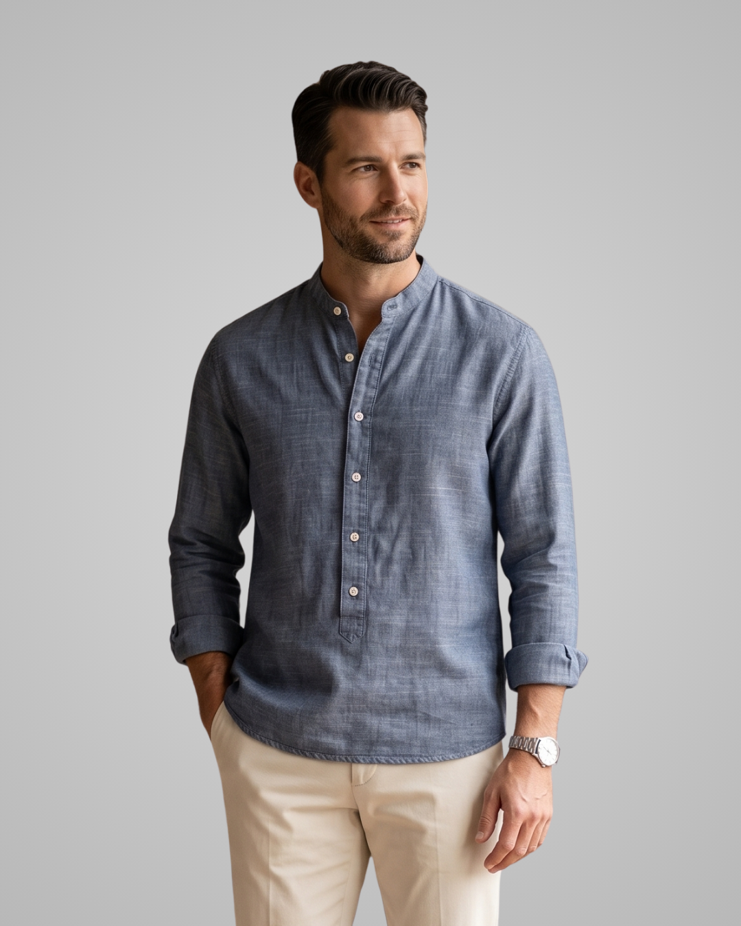 Man wearing a blue button-up shirt and beige pants on a gray background