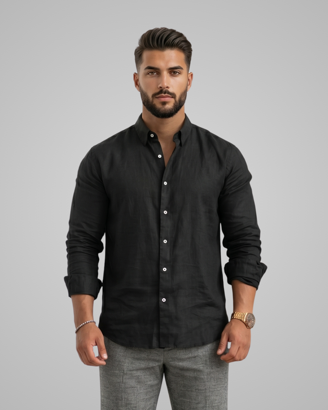 Man wearing a black button-up shirt and gray pants on a gray background