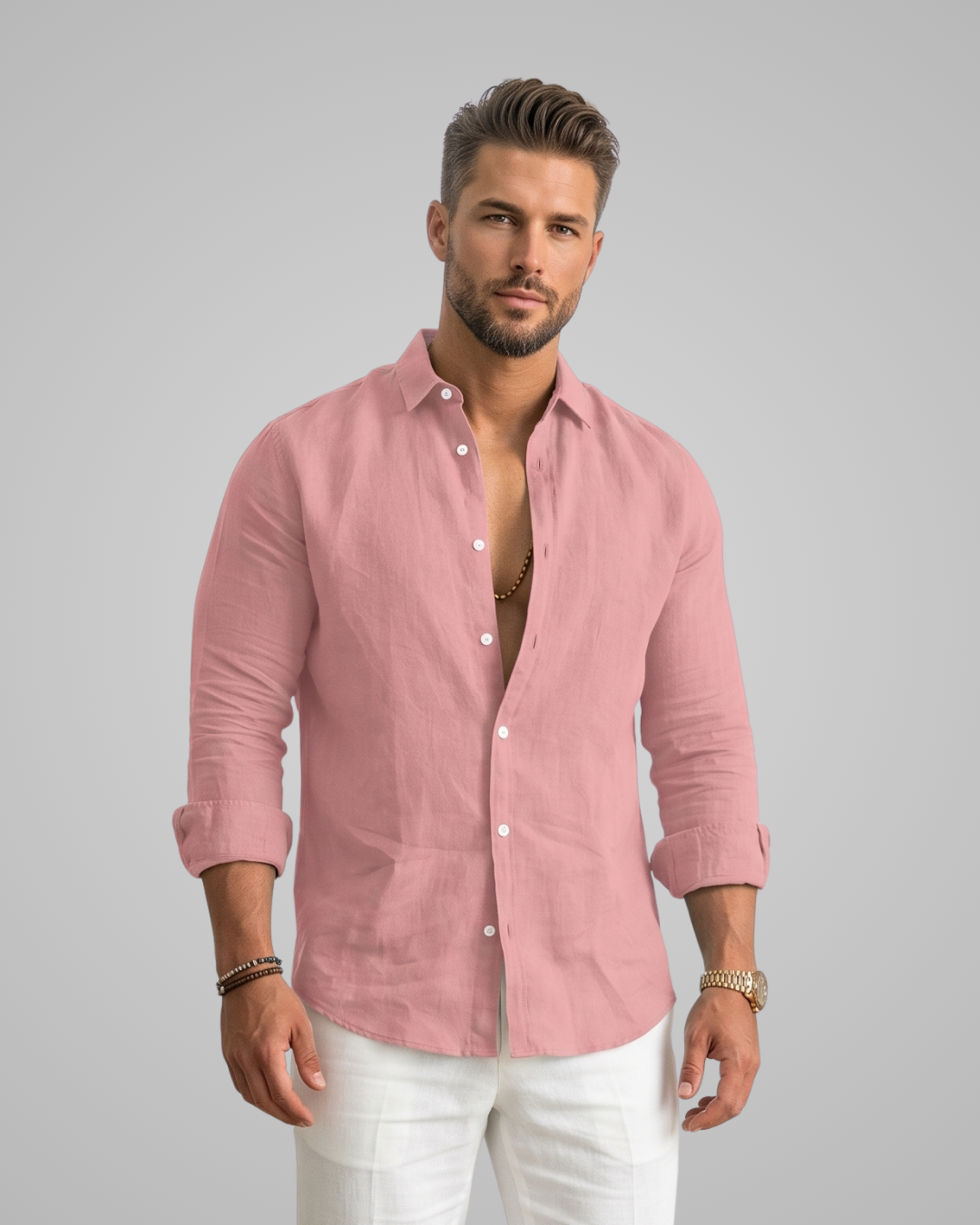 Man wearing a pink shirt with rolled-up sleeves and white pants on a gray background