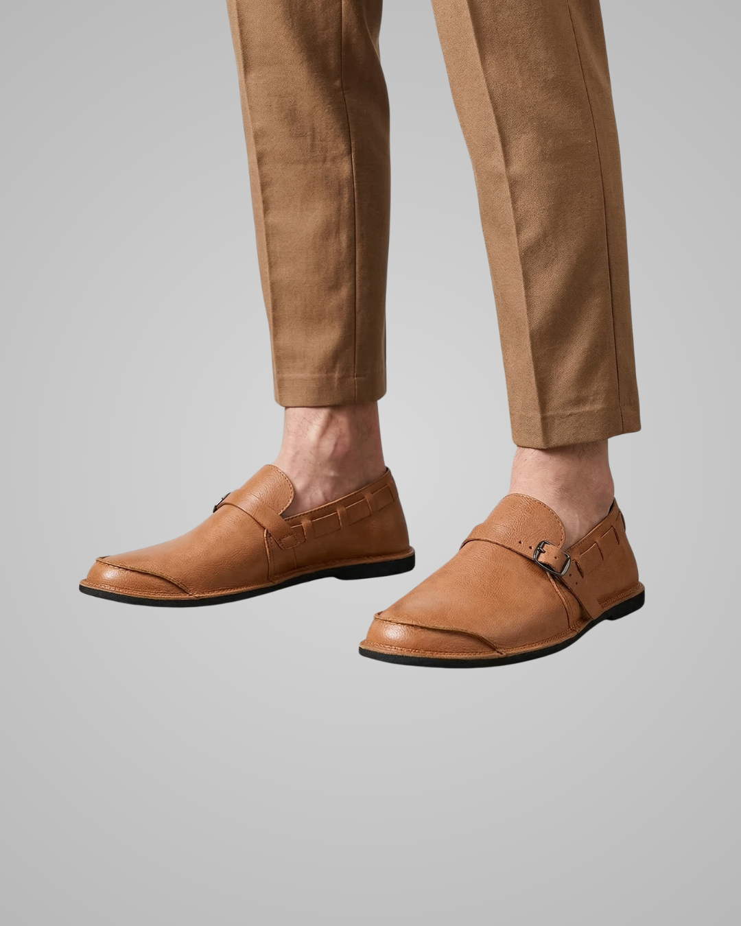 Brown loafers worn with beige pants on a gray background