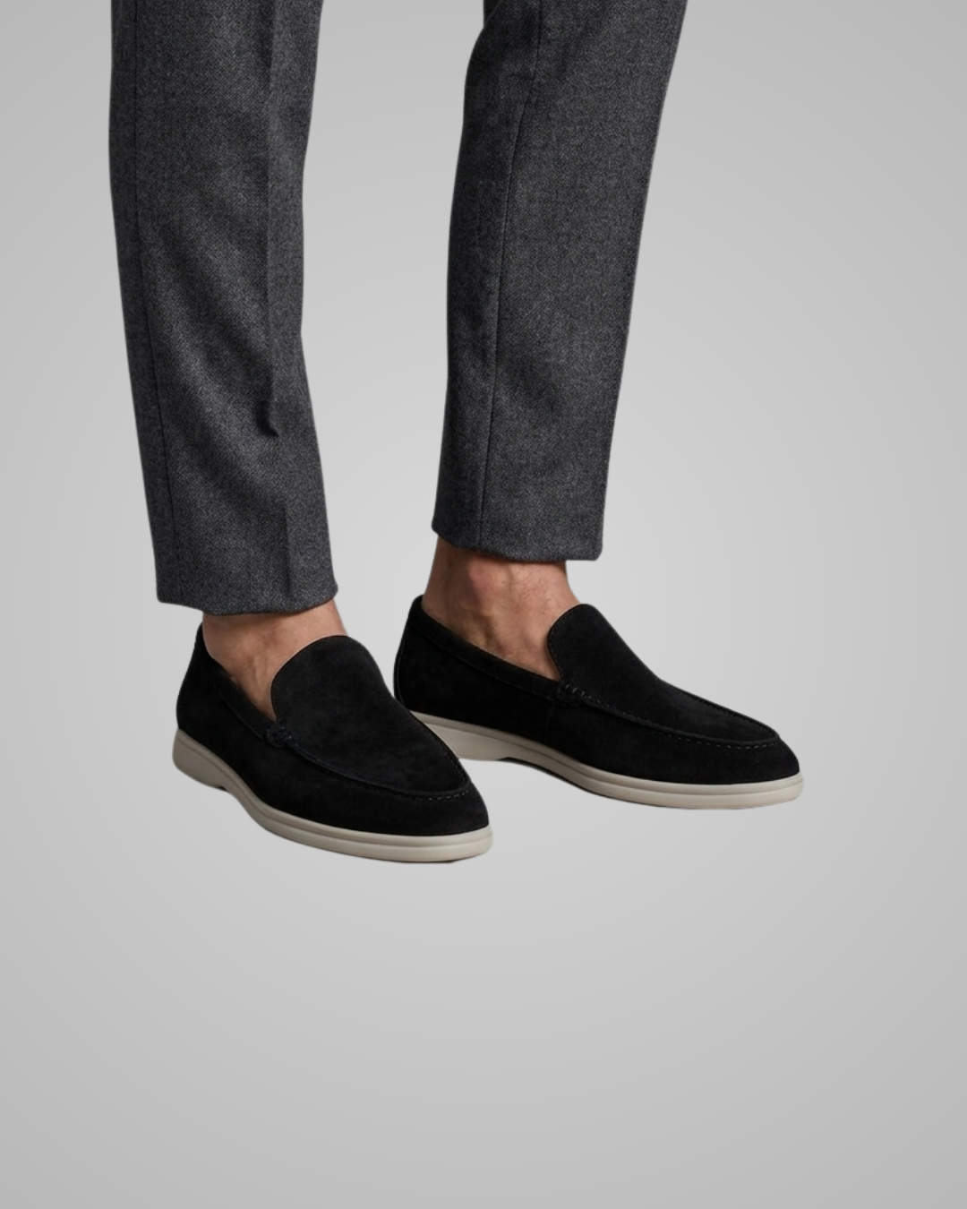 Black loafers worn with gray pants on a light gray background
