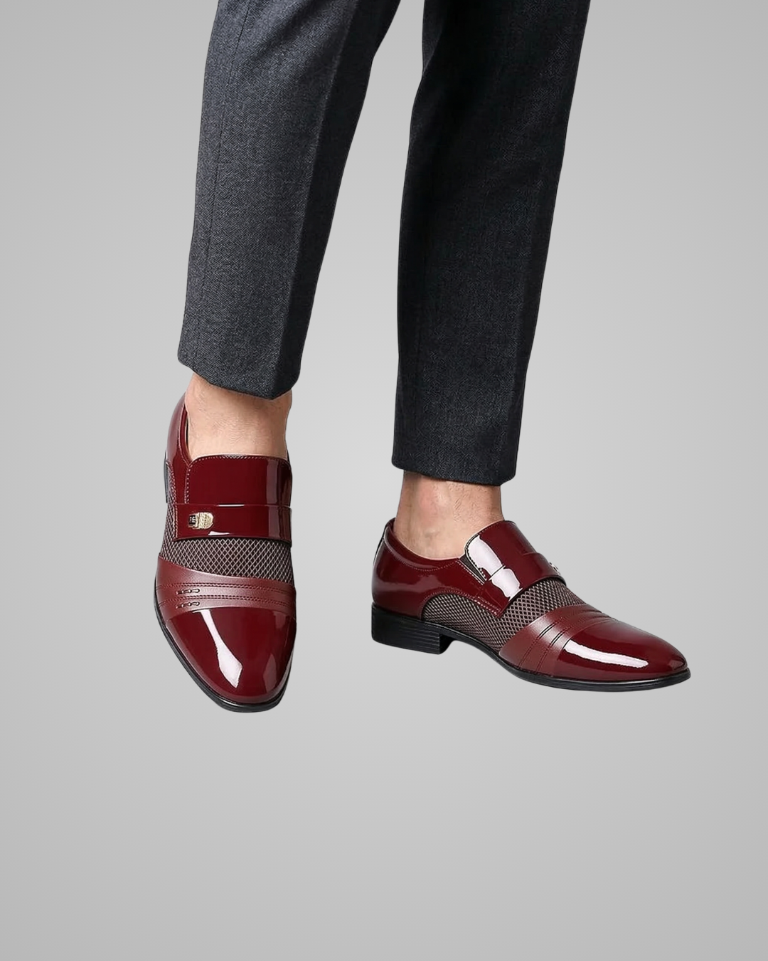 Burgundy dress shoes worn with dark gray pants on a light gray background