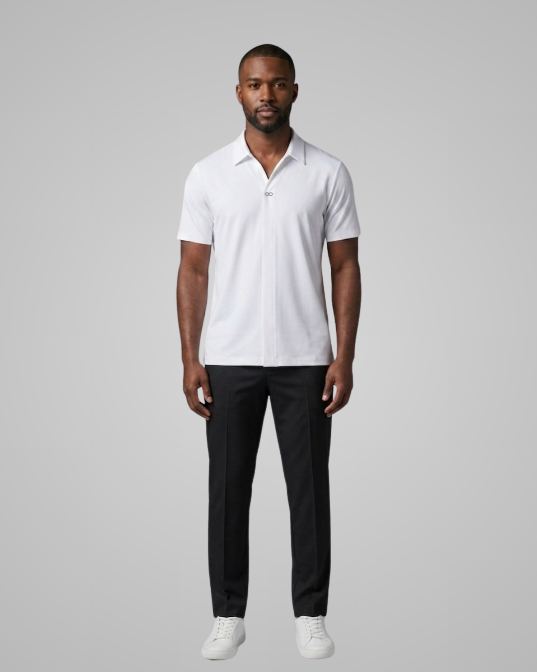 Man wearing a white polo shirt and black pants on a gray background