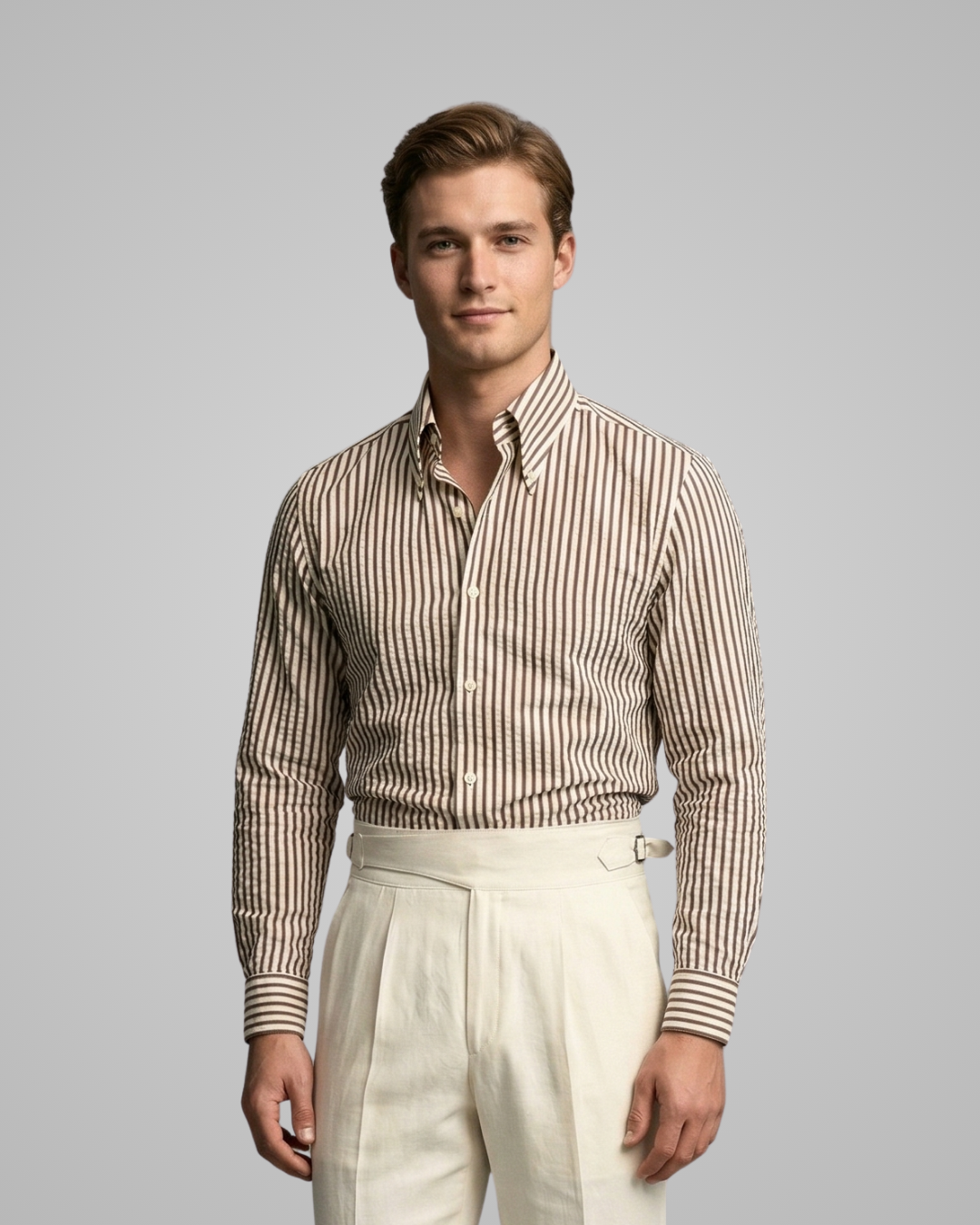 Man wearing a striped shirt and white pants against a gray background