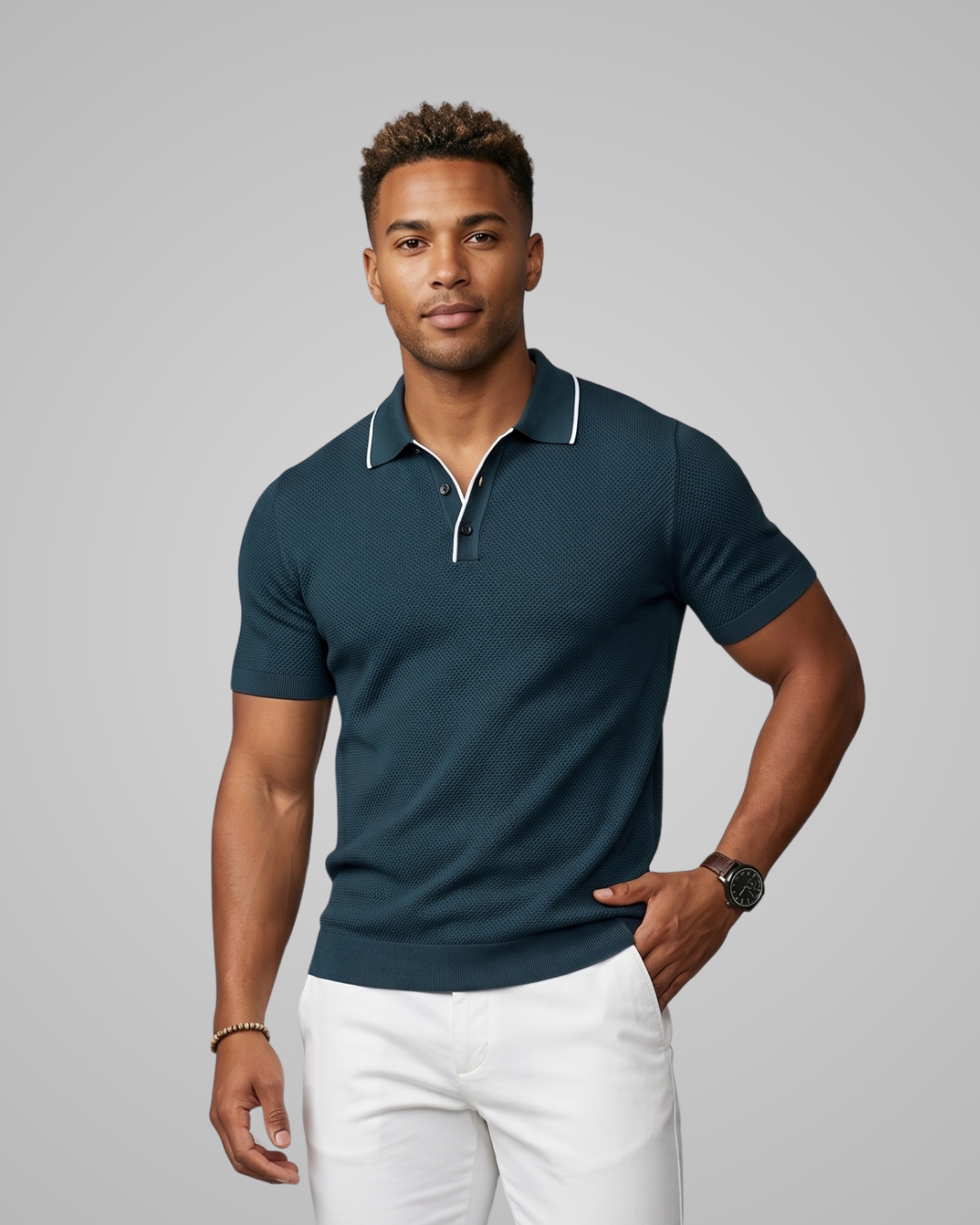 Man wearing a dark blue polo shirt and white pants against a gray background