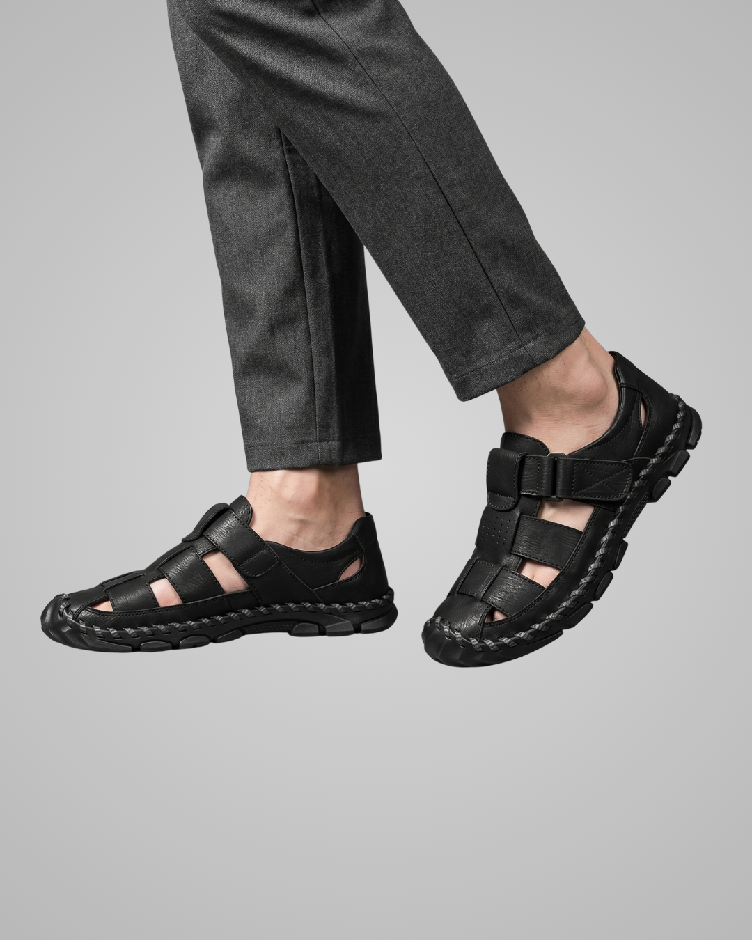 Black sandals worn with gray pants on a light gray background