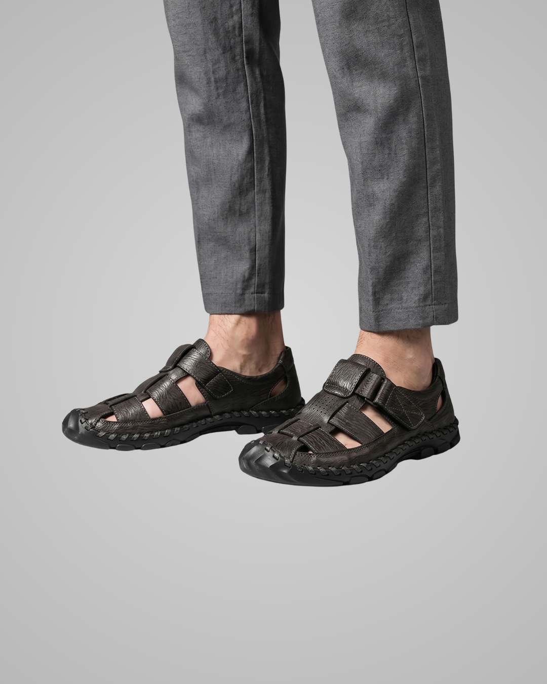 Black sandals worn with gray pants on a light gray background