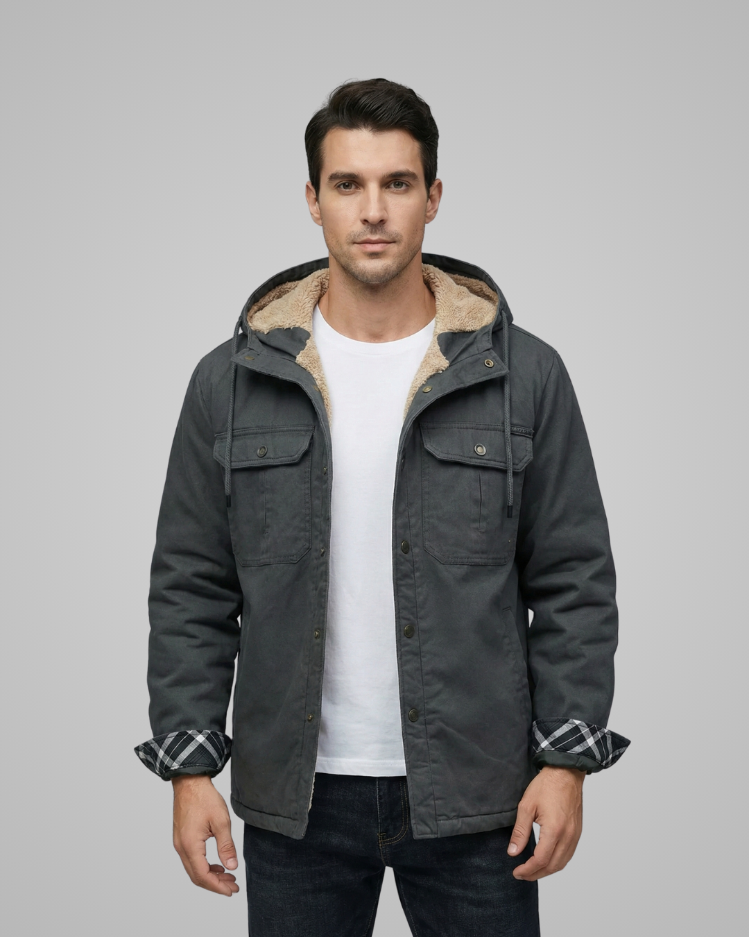 Man wearing a dark gray jacket with a hood on a gray background