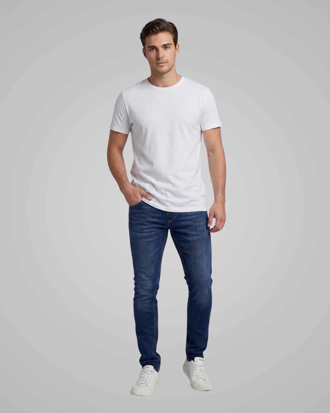 Man wearing a white t-shirt and blue jeans on a gray background