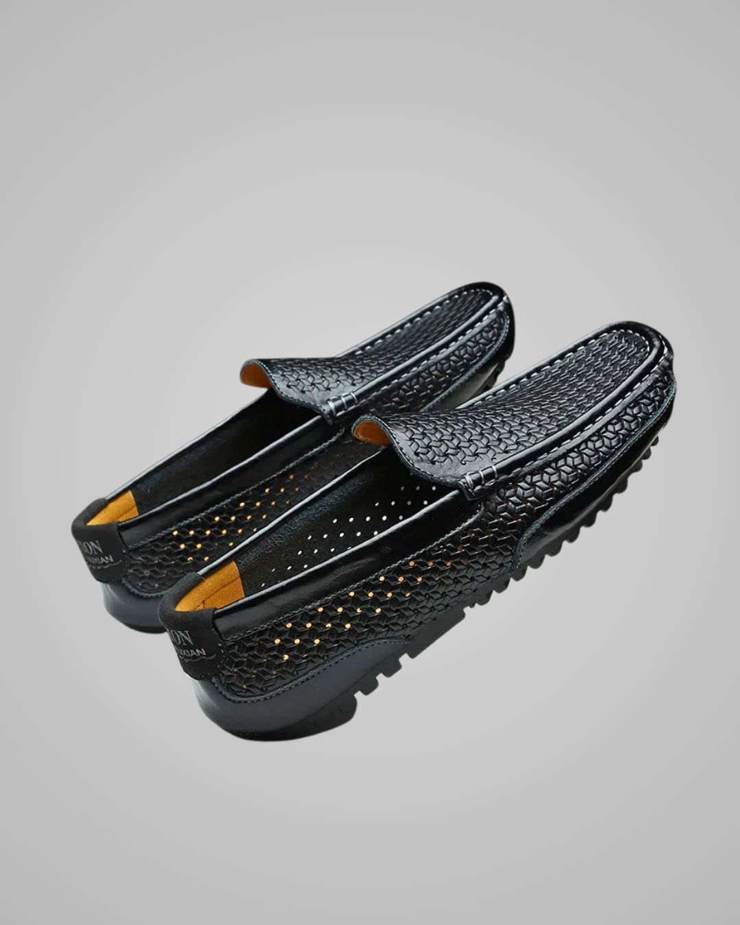 Black slip-on shoes with textured surface on a gray background