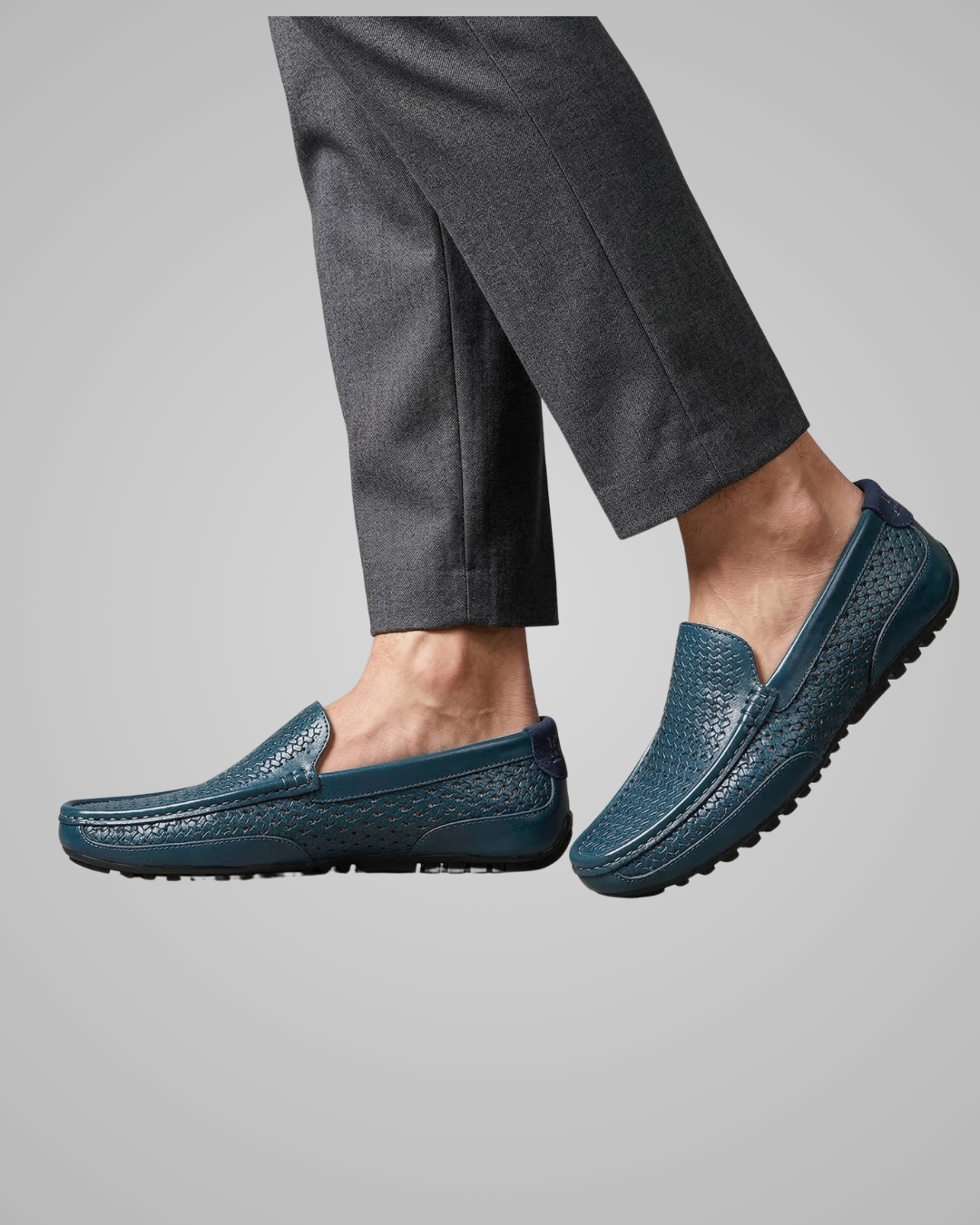 Person wearing navy blue slip-on shoes with textured sole on a gray background