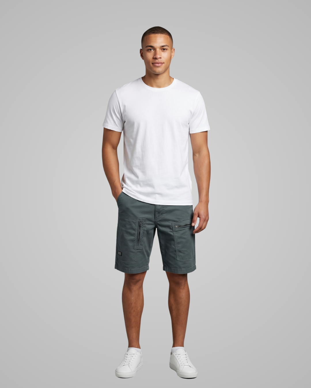 Man wearing a white t-shirt and gray shorts on a gray background