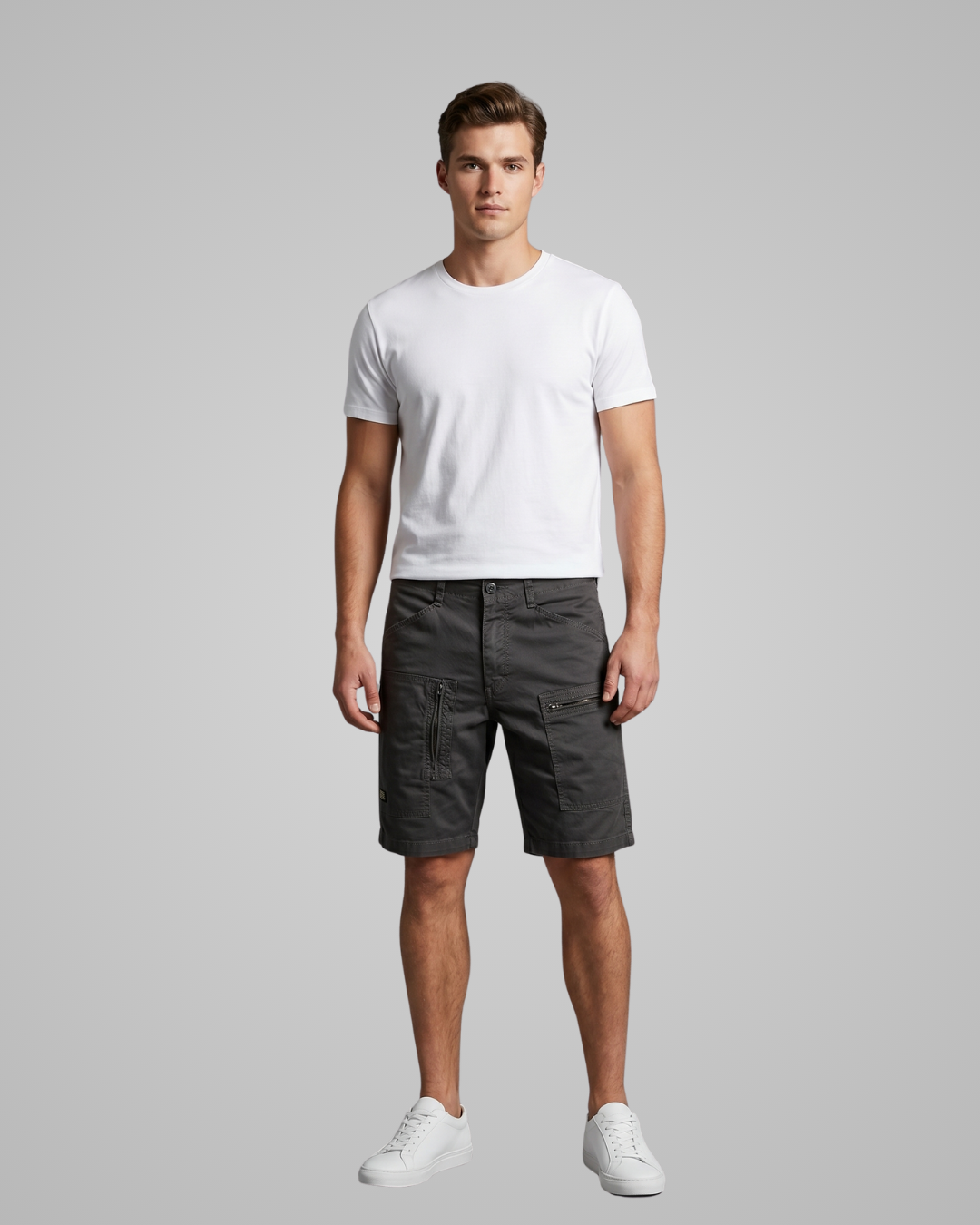 Man wearing a white t-shirt and dark shorts on a gray background