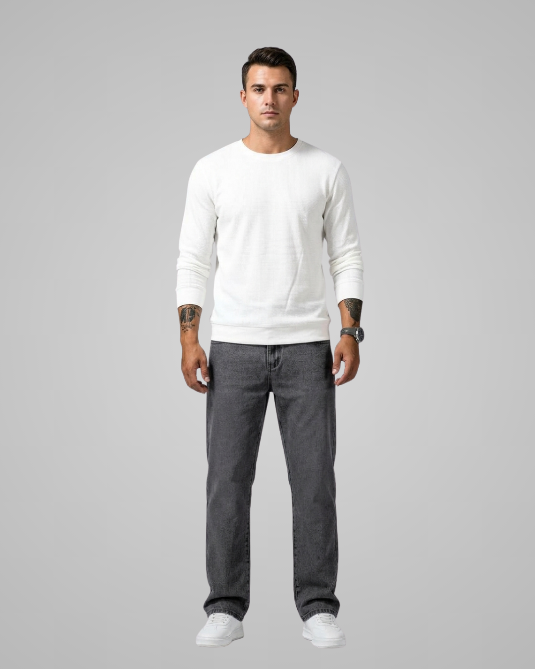 Man wearing a white sweater and gray pants on a gray background