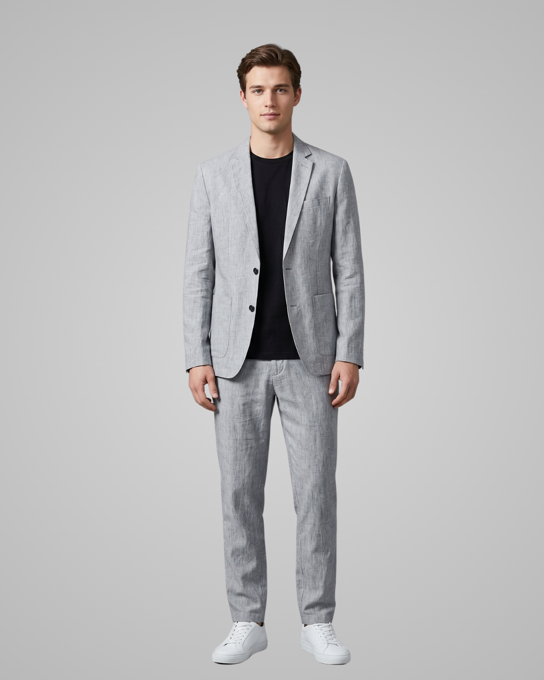 Man wearing a gray suit with a black shirt on a plain background