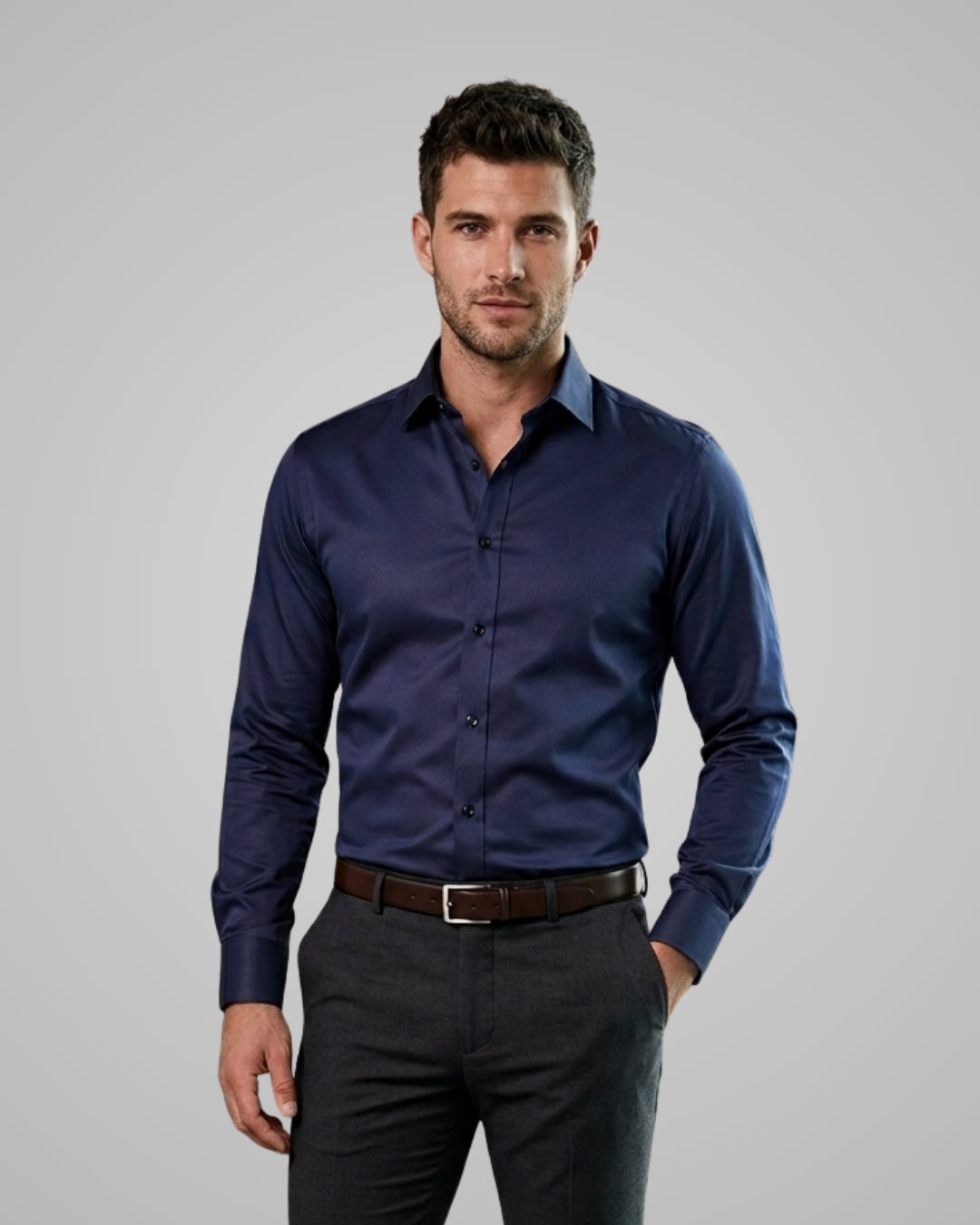 Man wearing a navy blue dress shirt and dark gray pants on a gray background