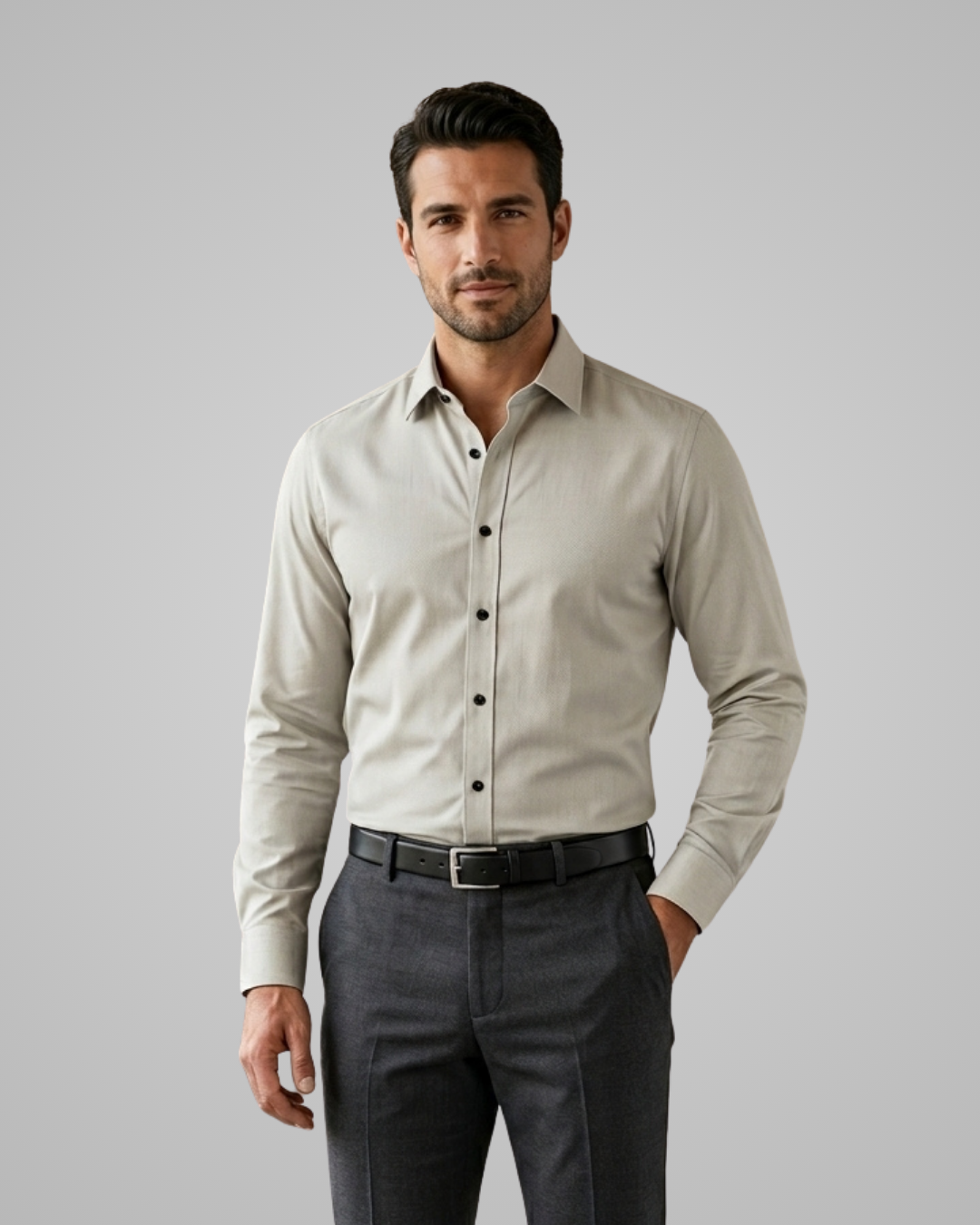 Man wearing a light gray dress shirt and dark gray pants on a plain background