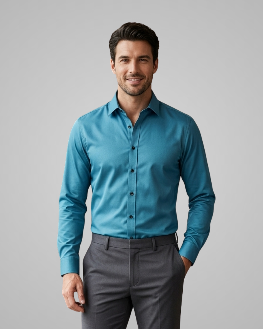 Man wearing a blue dress shirt and gray pants against a gray background