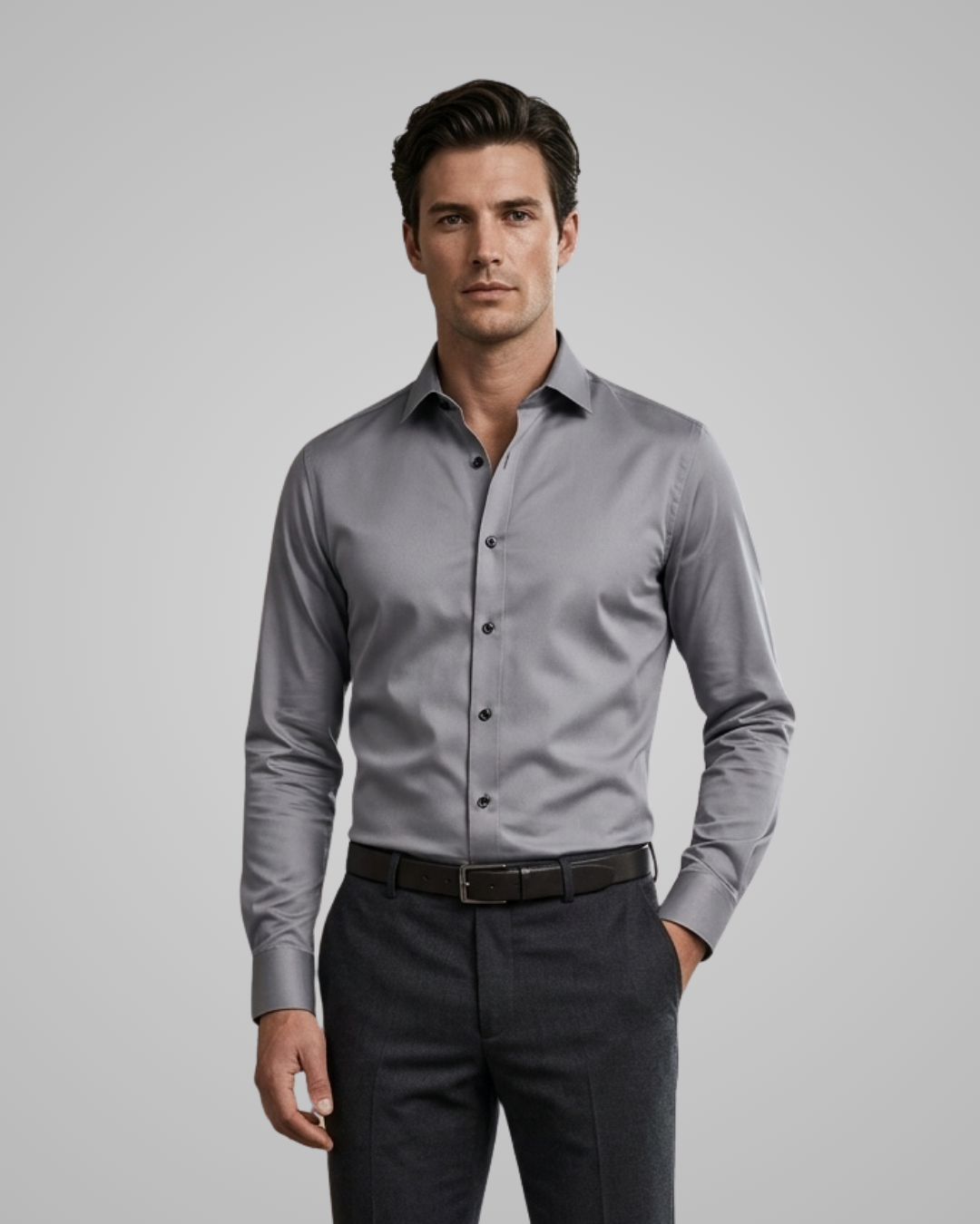 Man wearing a gray dress shirt and dark pants on a gray background
