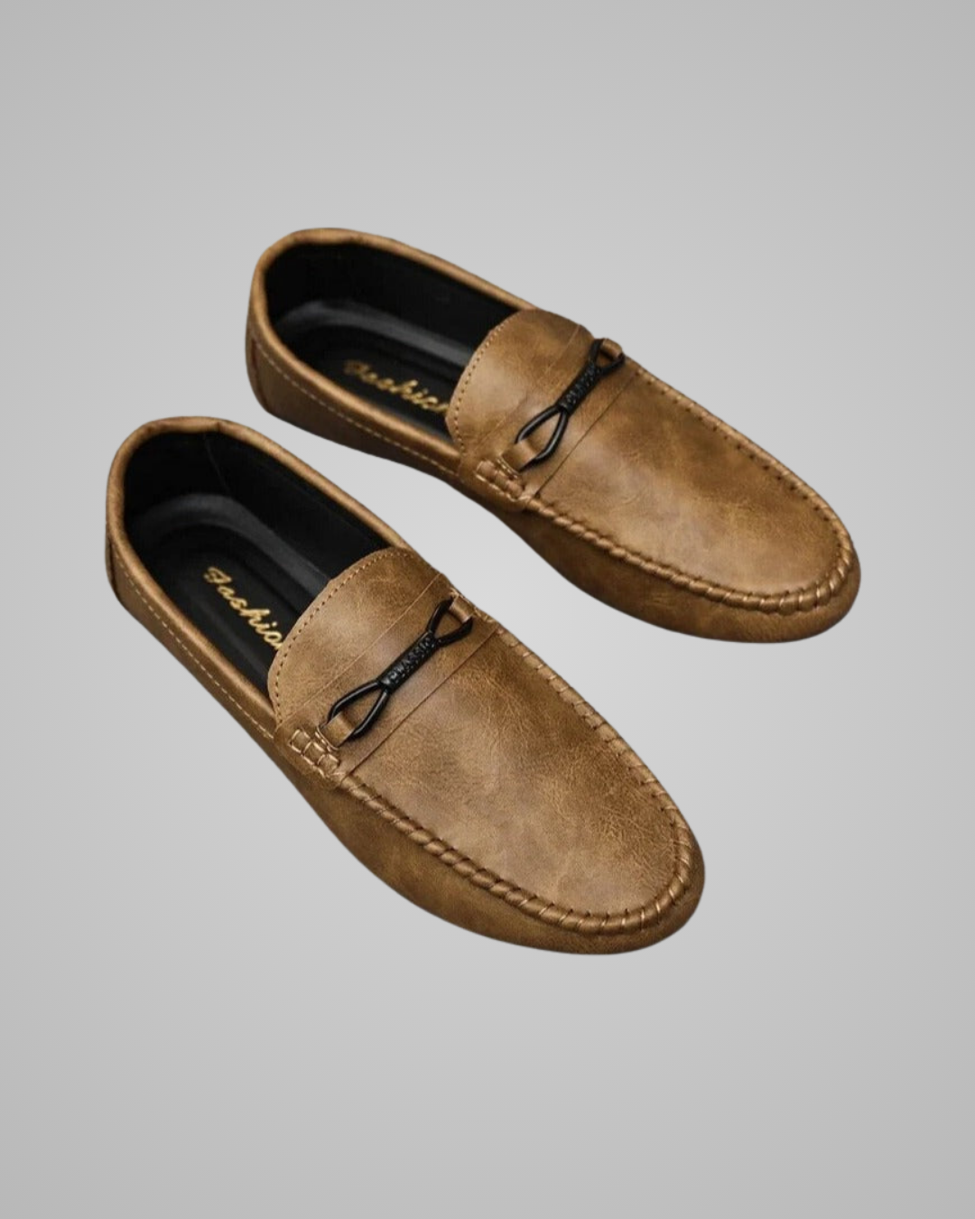 A pair of men's tan suede penny loafers with black leather tie details, displayed on a neutral gray background.
